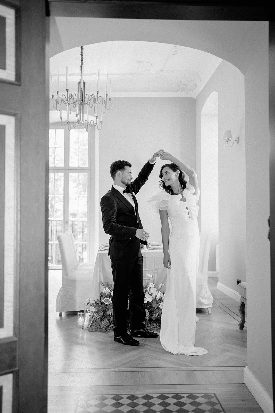 Ein Paar tanzt in einem eleganten Raum bei einer Hochzeitsfeier, Schwarz-Weiß-Fotografie.