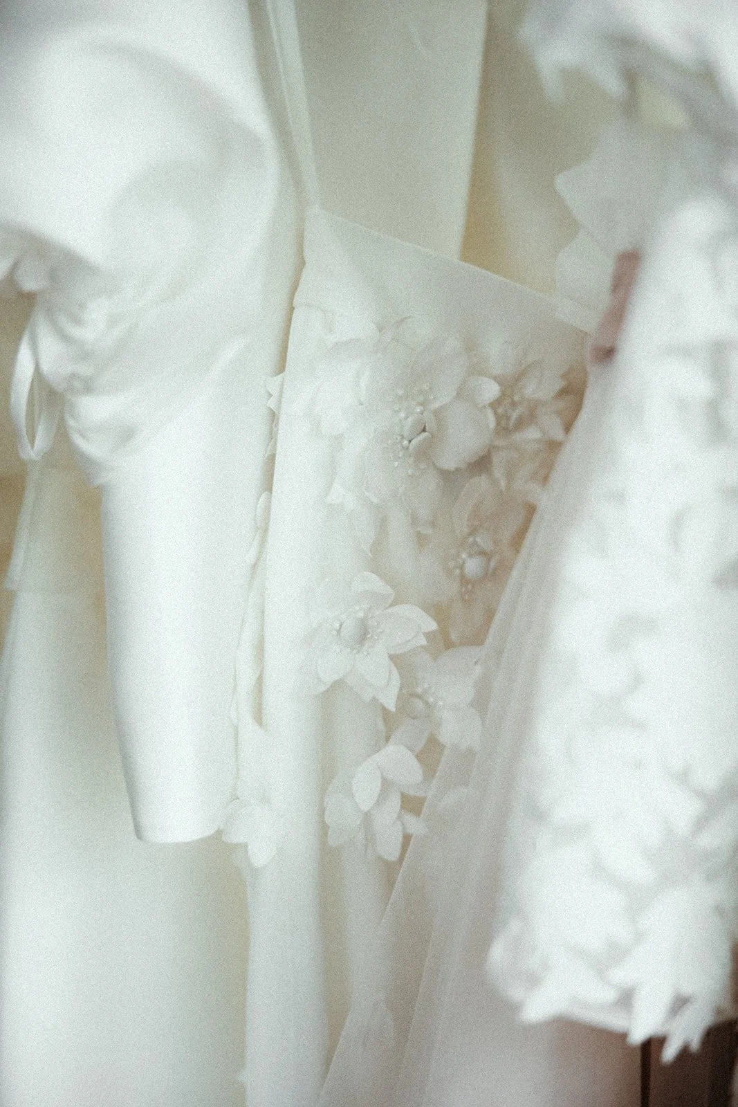 Nahaufnahme eines weißen Kleides mit floralen Spitzendetails.