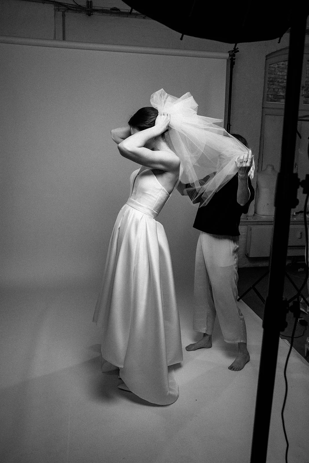 Model in einem Brautkleid während eines Fotoshootings. Sie steckt sich einen Schleier auf den Kopf.
