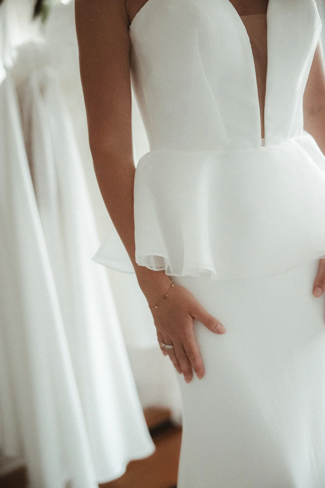Frau in elegantem weißen Kleid mit ärmellosem Design und tiefem Ausschnitt, Detailansicht.