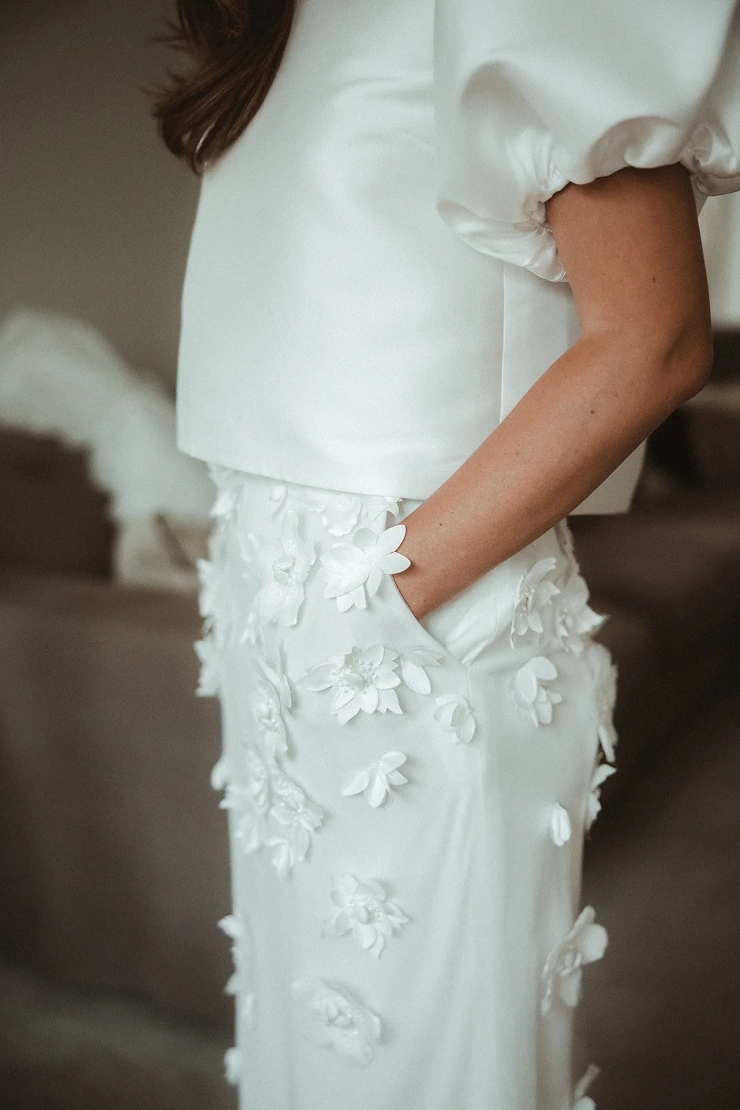Frau in weißem Kleid mit Blumenstickerei und Puffärmeln.