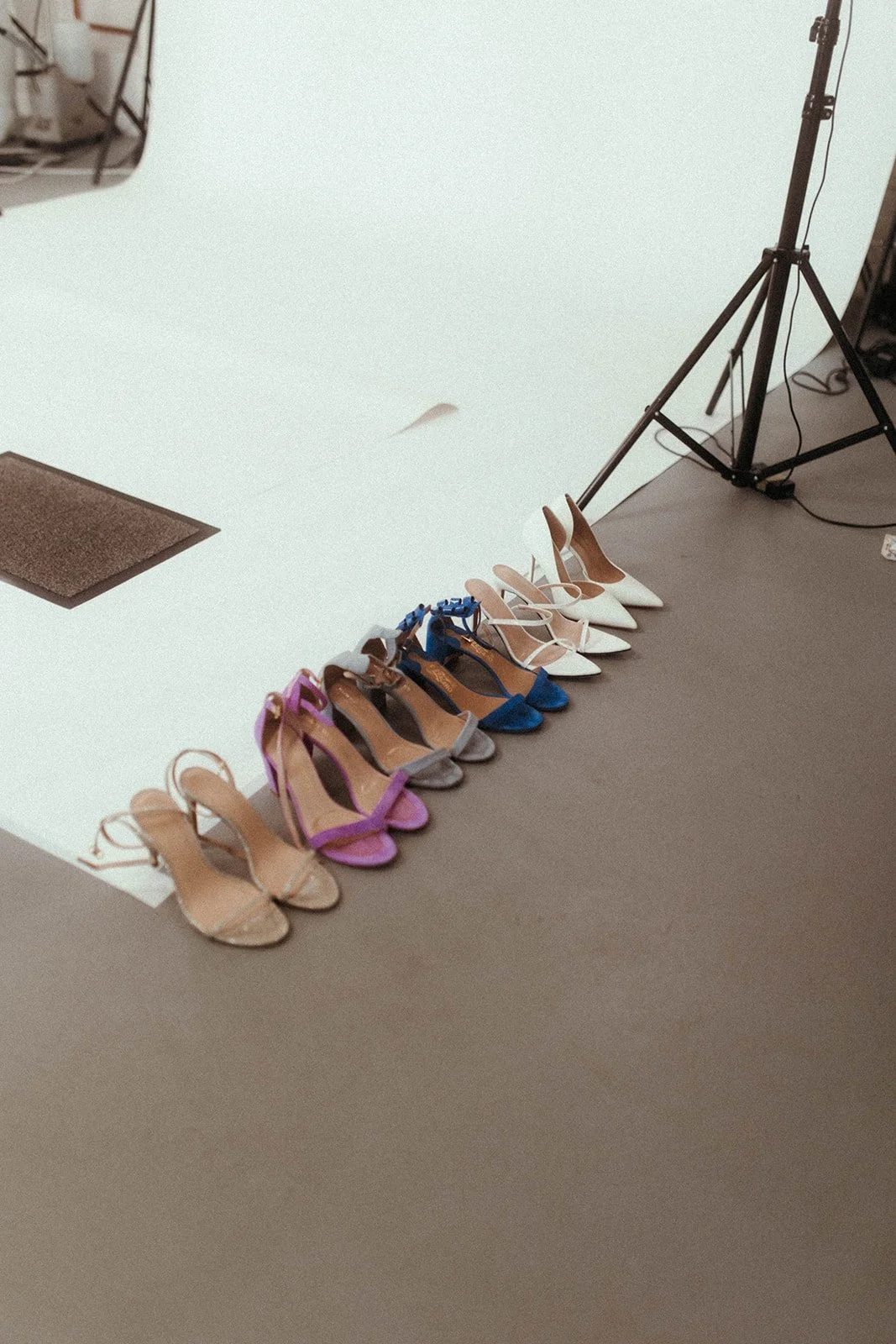 Verschiedene High Heels in verschiedenen Farben und Stilen auf dem Boden, wahrscheinlich für ein Fotoshooting oder eine Modenschau bereitgestellt.