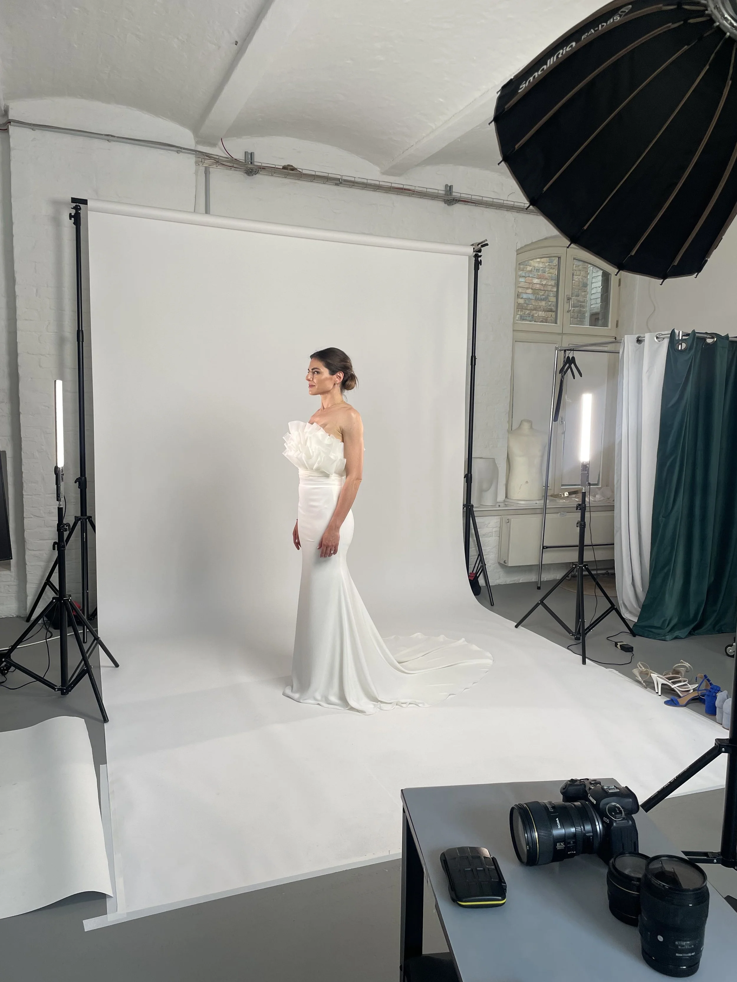 Frau in einem weißen Brautkleid während eines Fotoshootings in einem Fotostudio mit professioneller Ausrüstung.