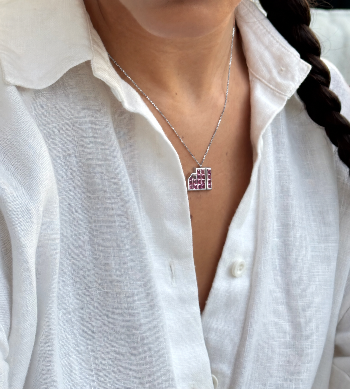 ALLAH Pink Sapphire Pendant in 18K white gold worn on the neck, showing its geometric calligraphy form and pink sapphire setting.
