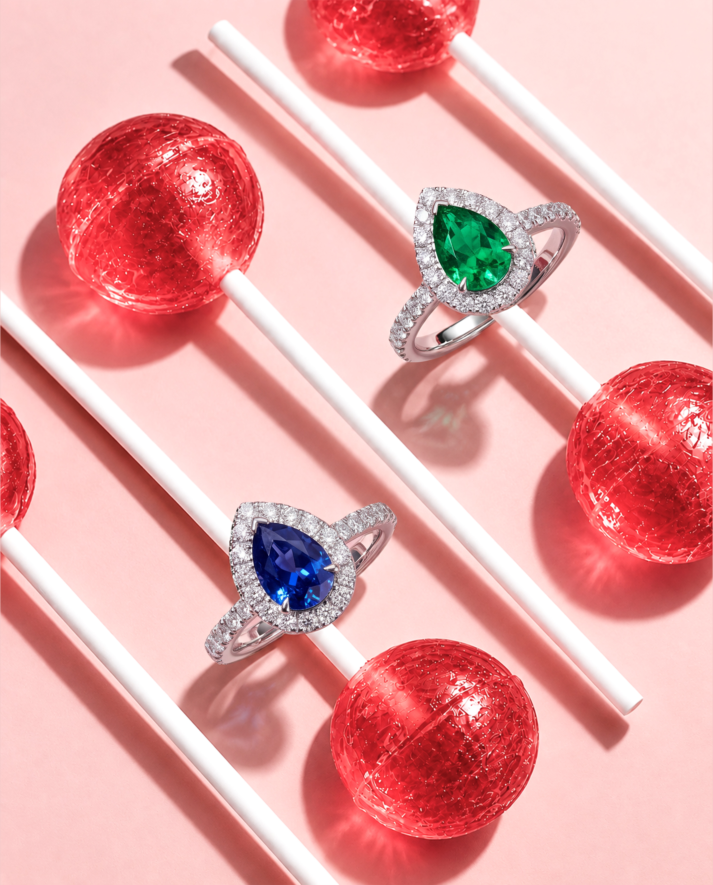VIVI pear-shaped emerald and blue sapphire rings surrounded by natural round diamonds in a styled pink campaign setting.