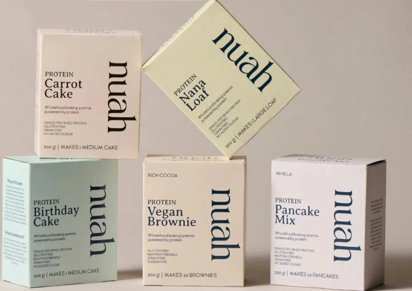 Five boxes of vegan baking mixes, including carrot cake, Nana Loaf, birthday cake, vegan brownie, and pancake mix, arranged against a plain background.