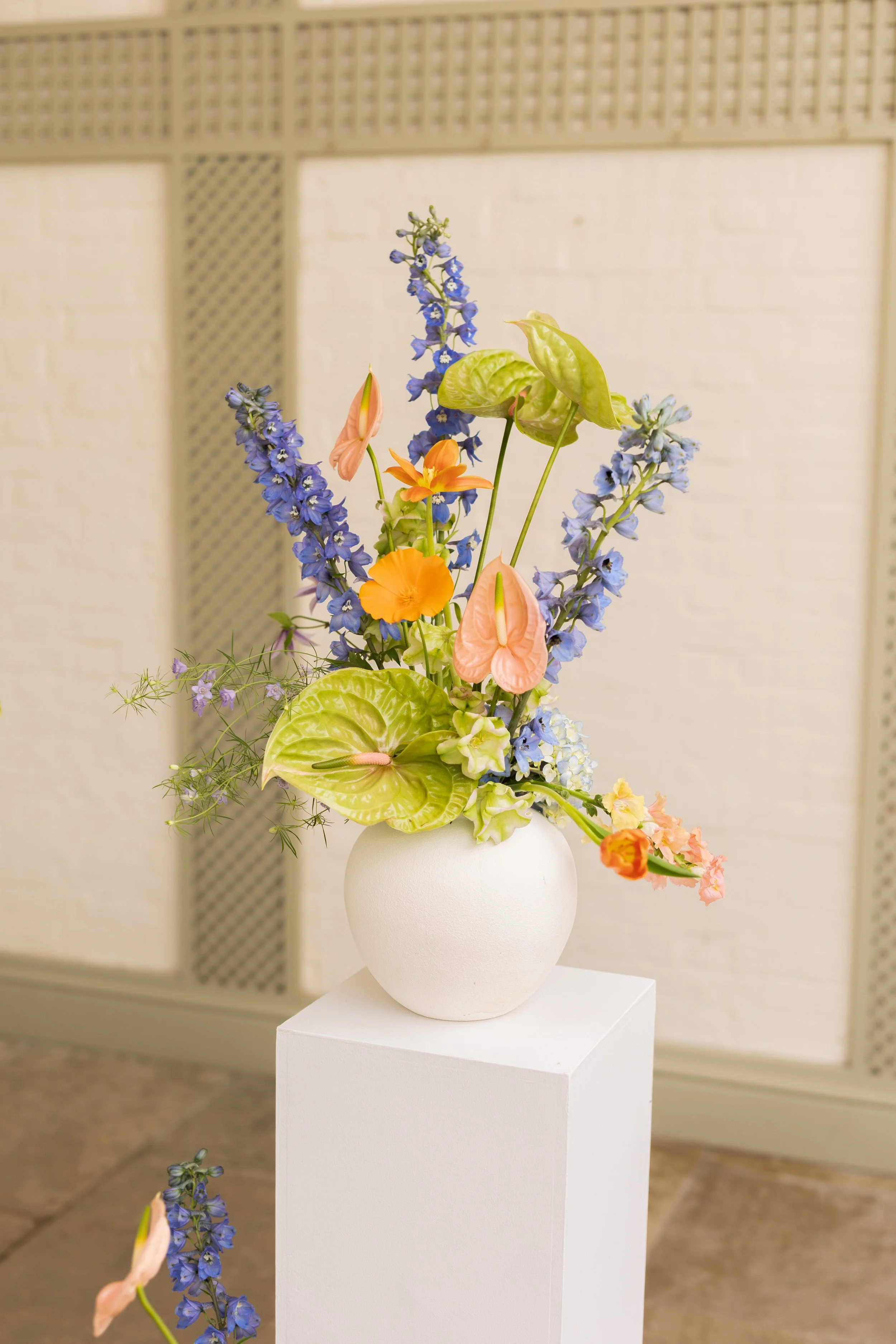 Colorful floral arrangement in a white vase on a pedestal.