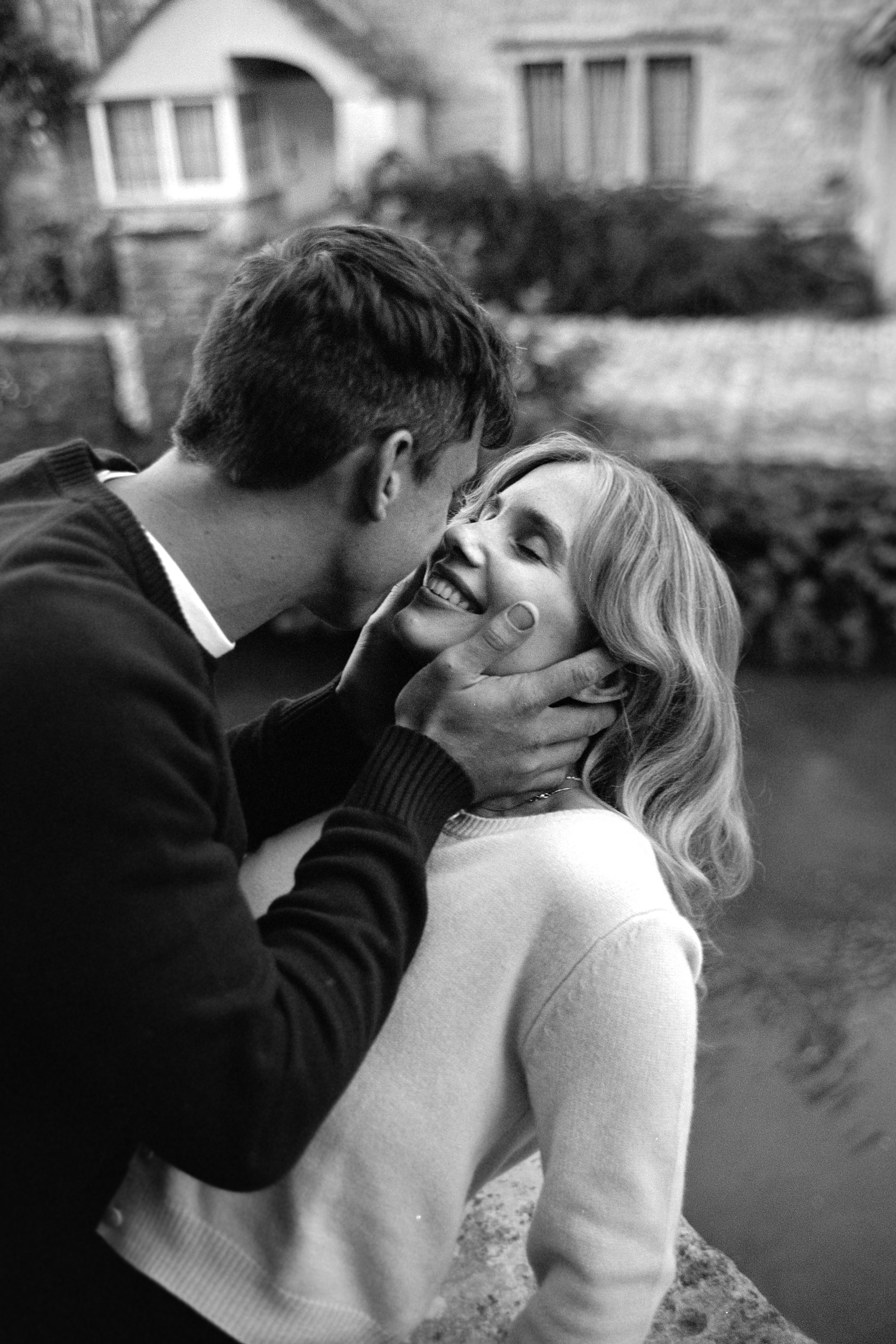 A man and woman sharing a joyful moment outdoors, with the man holding the woman's face as they smile at each other.