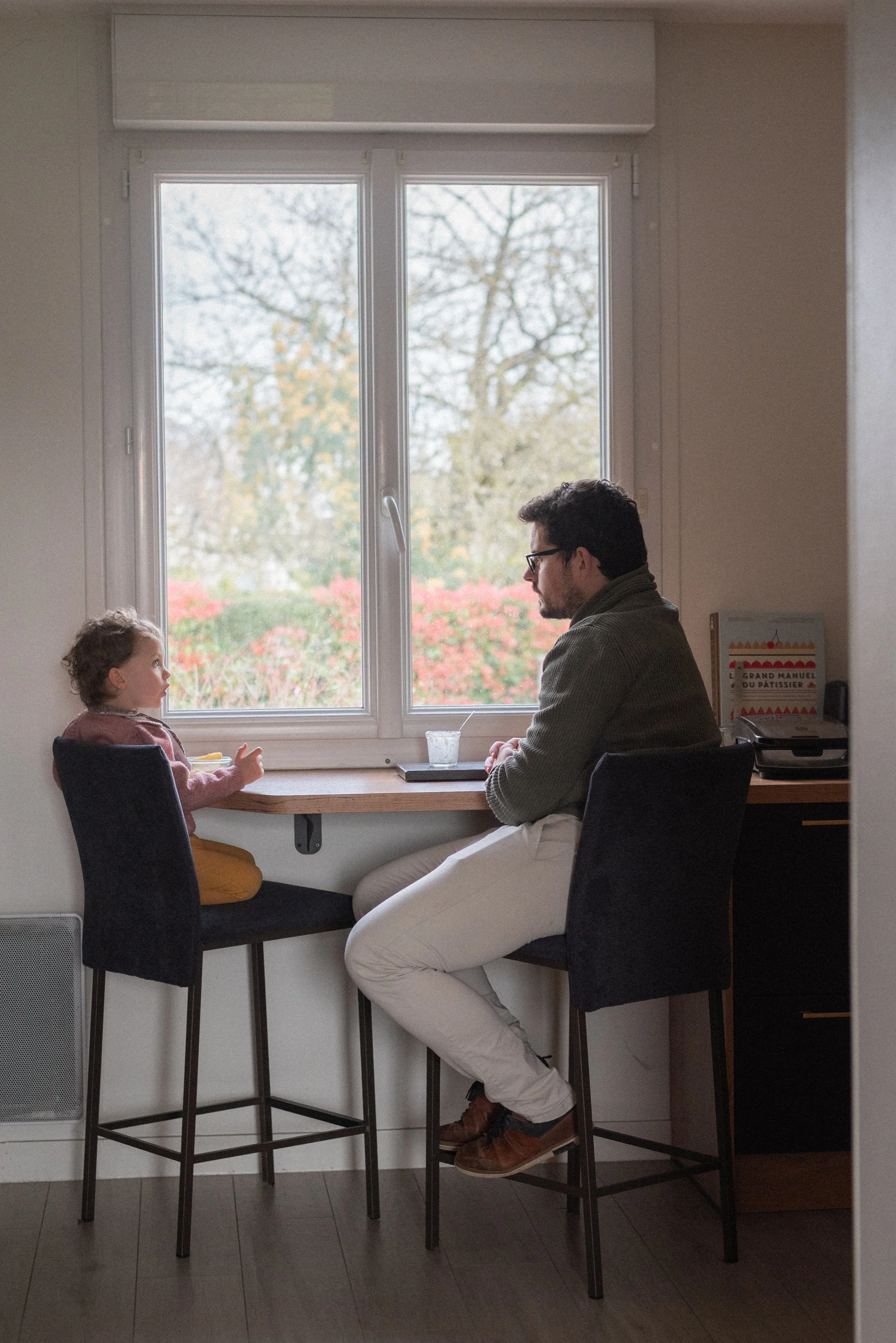 une petite fille assise et son papa assis face à face