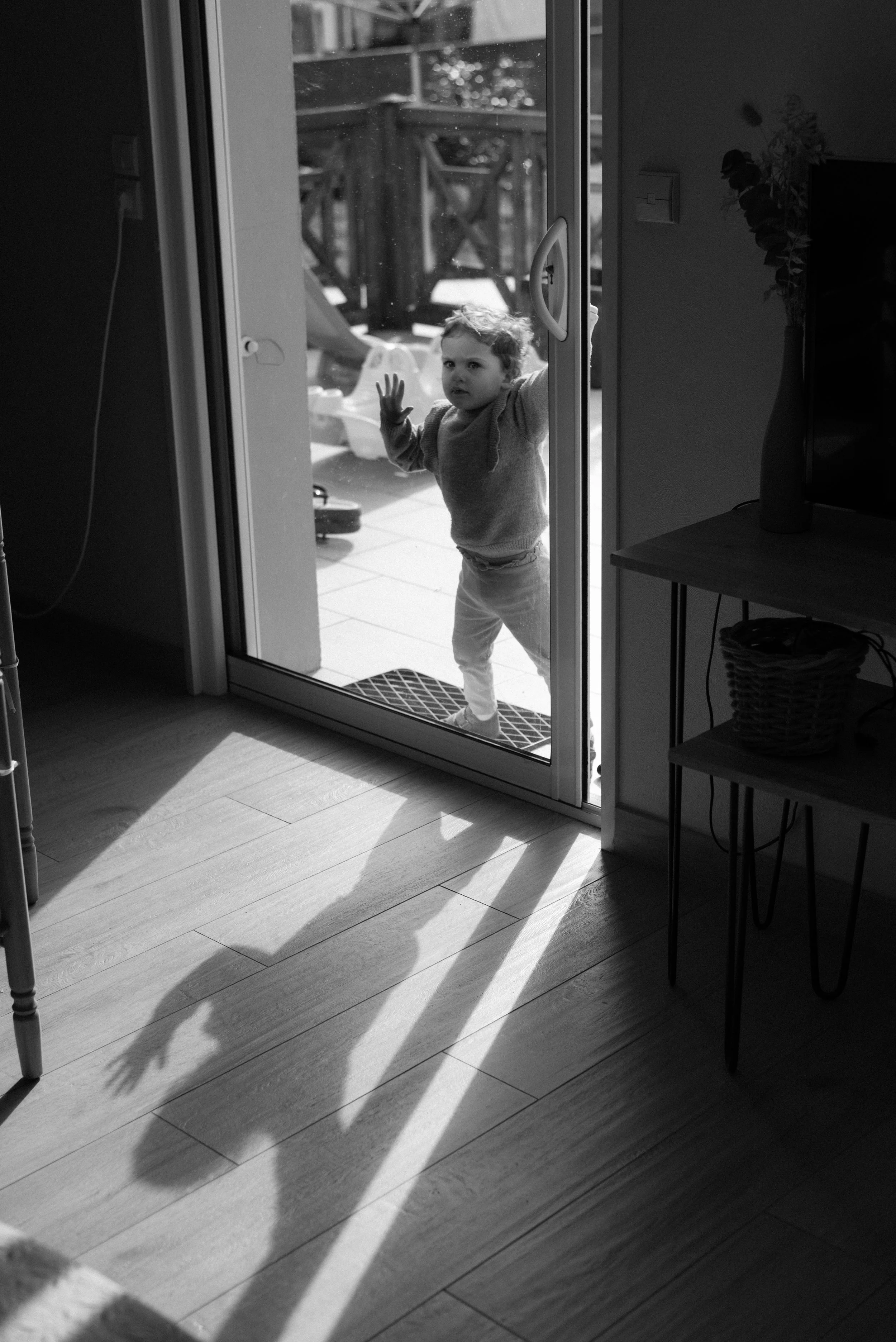 une petite fille derrière une vitre et son ombre