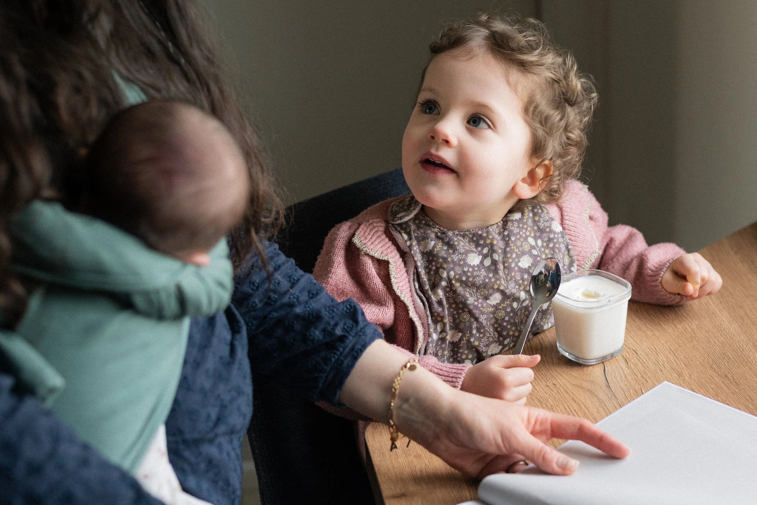 une petite fille à table regardant sa maman