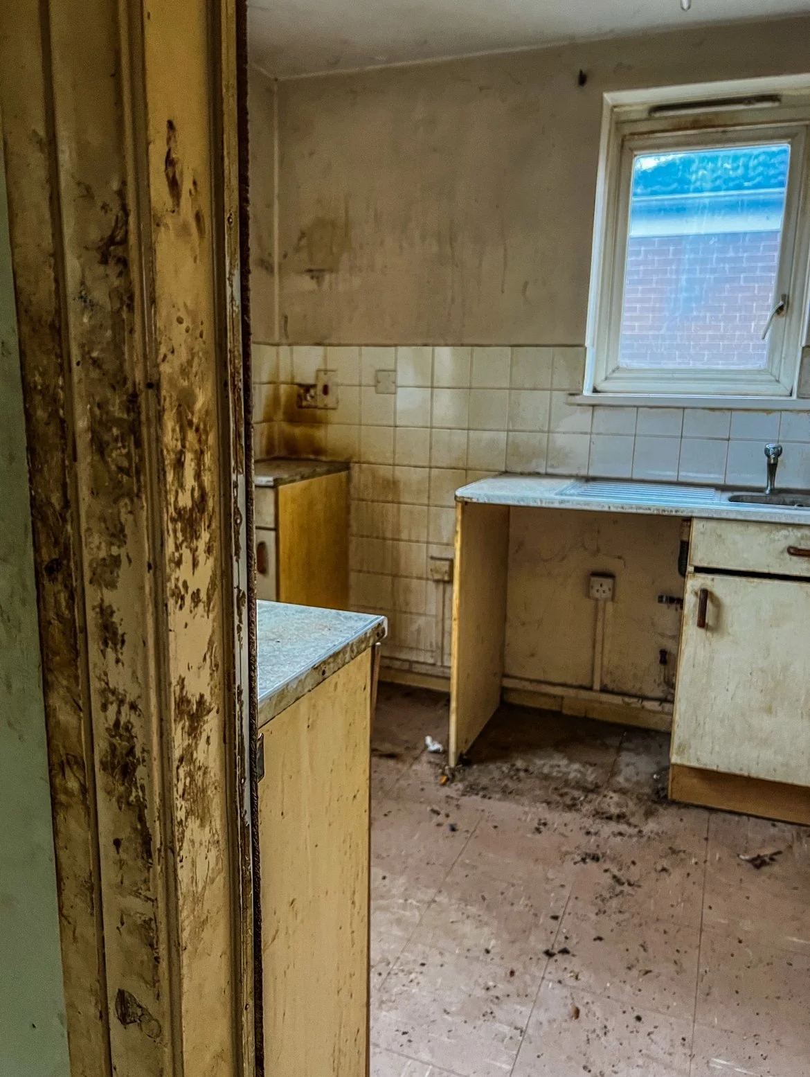 An image of a filthy kitchen, with dirty marks on the walls door frame.