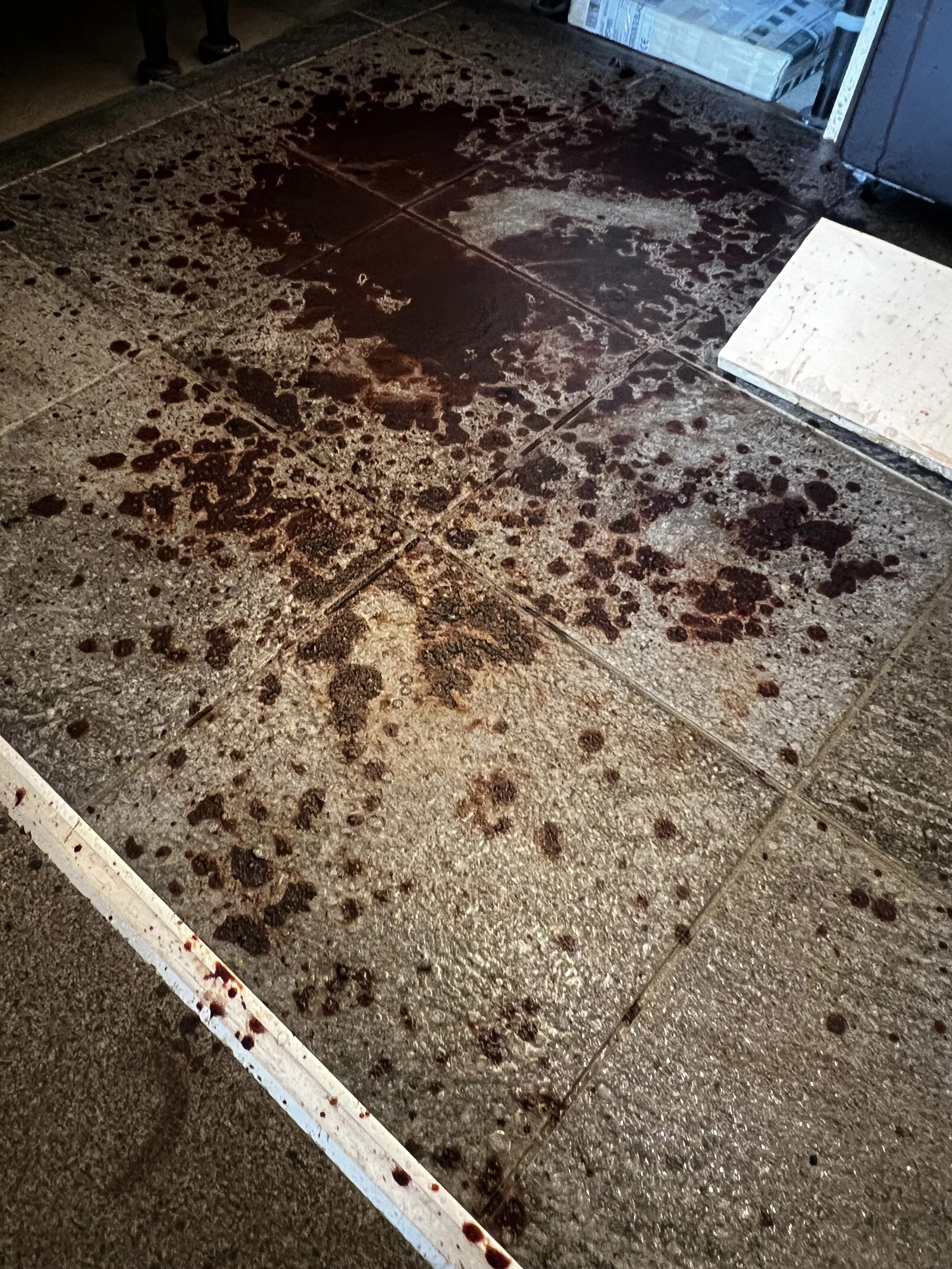 Floor with dark red liquid stains in indoor setting.