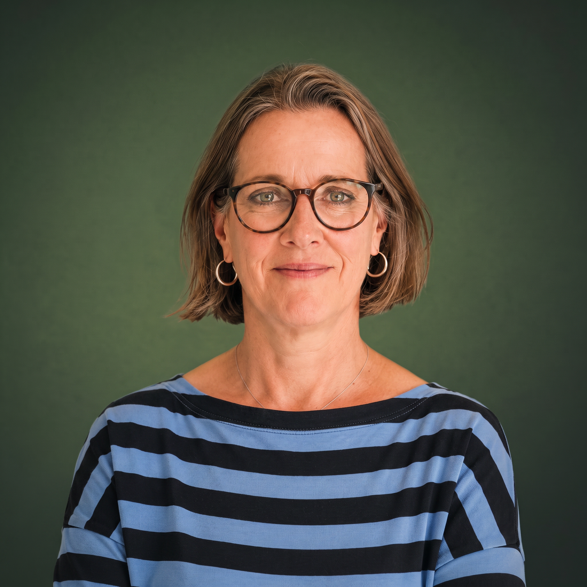 Nahaufnahme des Gesichts einer Frau mit Brille, Schulterlangem Haar und einem blauen gestreiften Pullover vor grünem Hintergrund.