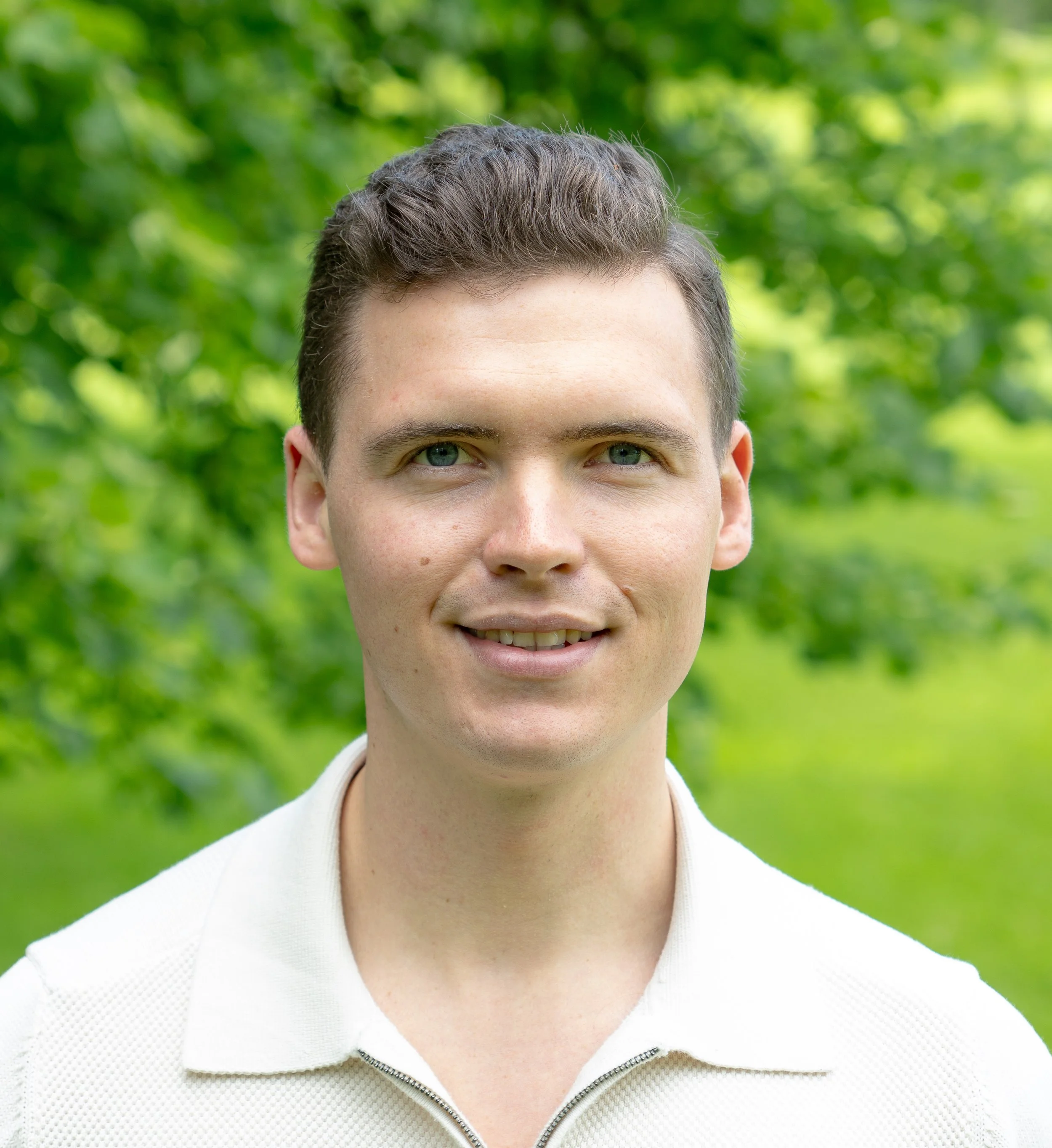 Ein Mann lächelt und befindet sich auf einer Grünfläche