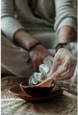 Person holding a steaming bowl of soup or tea with a wooden spoon.