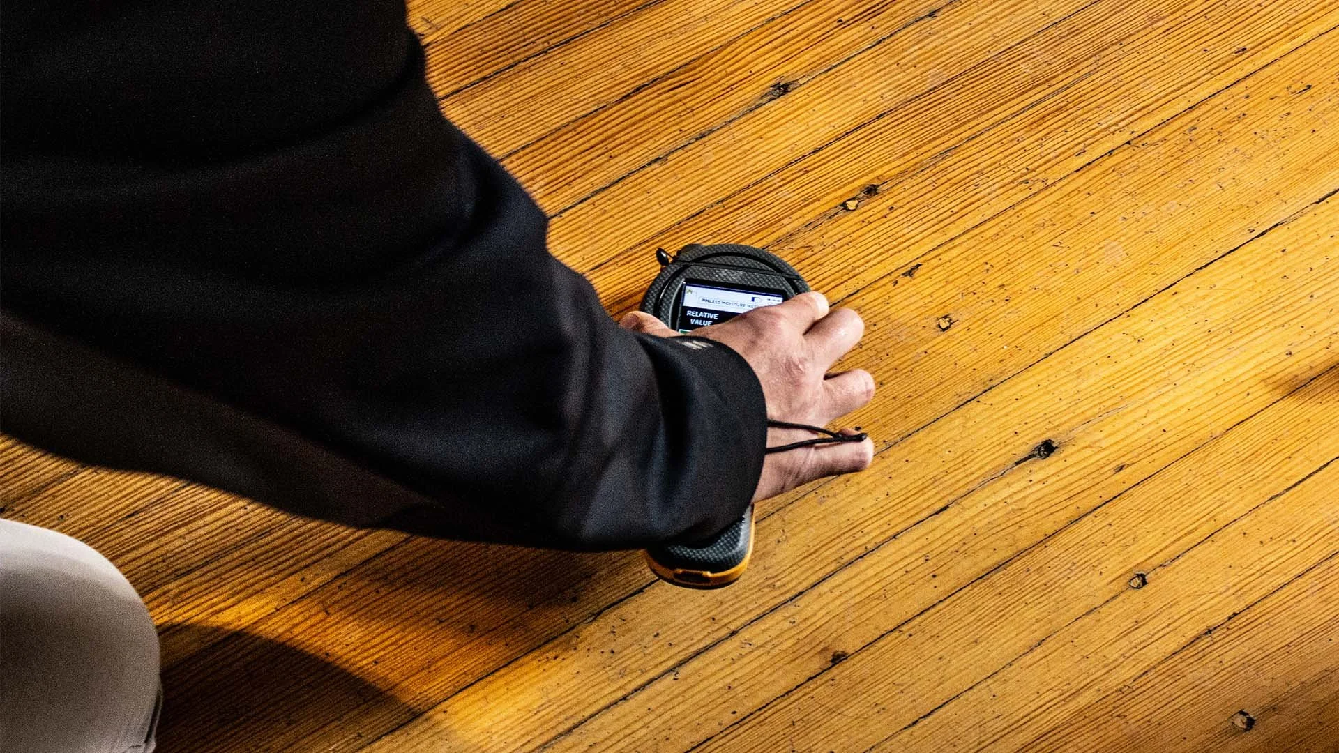 Technician using a moisture meter on hardwood flooring.