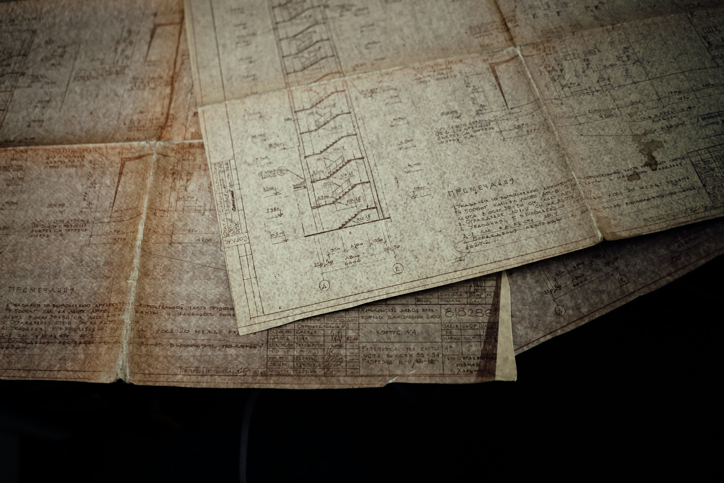 Old architectural blueprints and technical drawings spread out on a table.