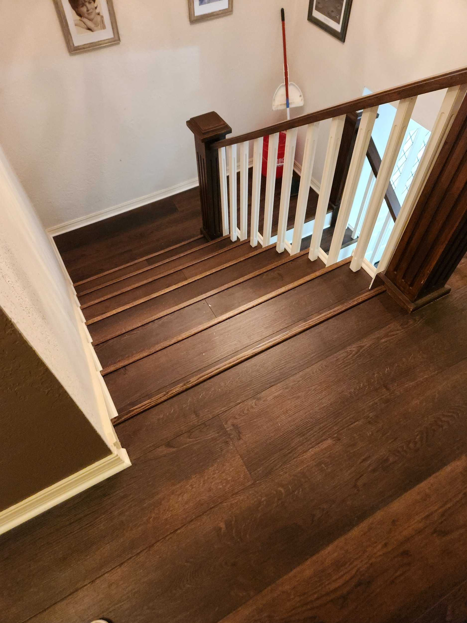Custom staircase and hallway renovation with luxury vinyl plank flooring and stained hardwood trim in Tulsa area home