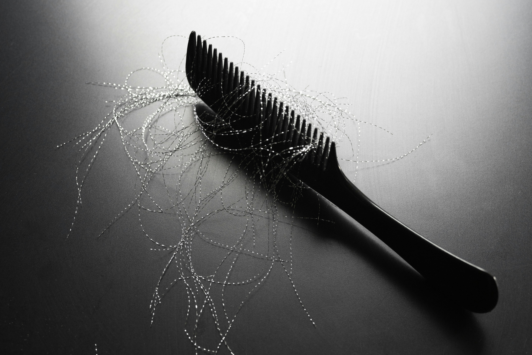Black and white photo of comb with hairs on table