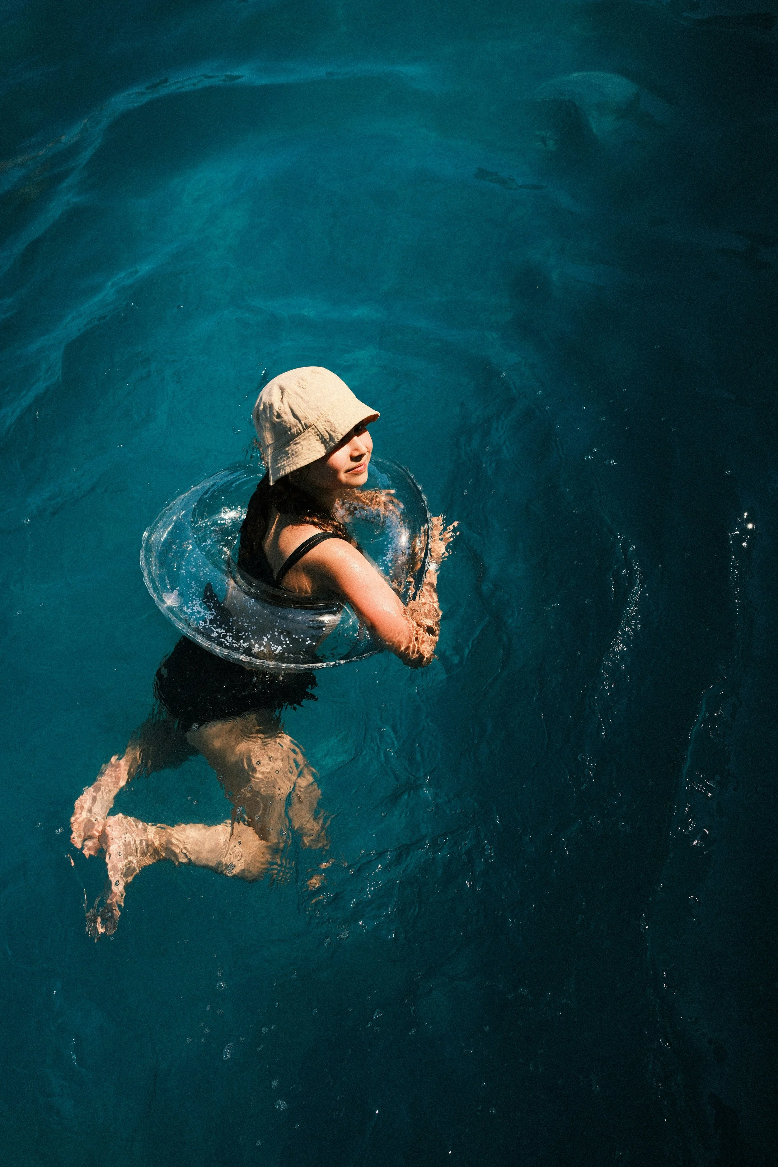 Woman in pool with float and hat