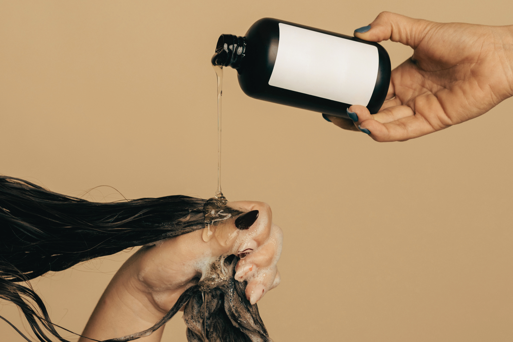 Shampoo dripping onto hair from a few inches above on gold background