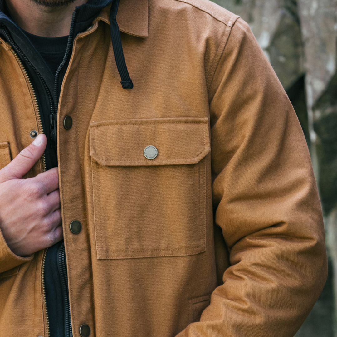 Person squatting next to a car, holding a blue cooler, wearing socks and worn slip-on sandals.