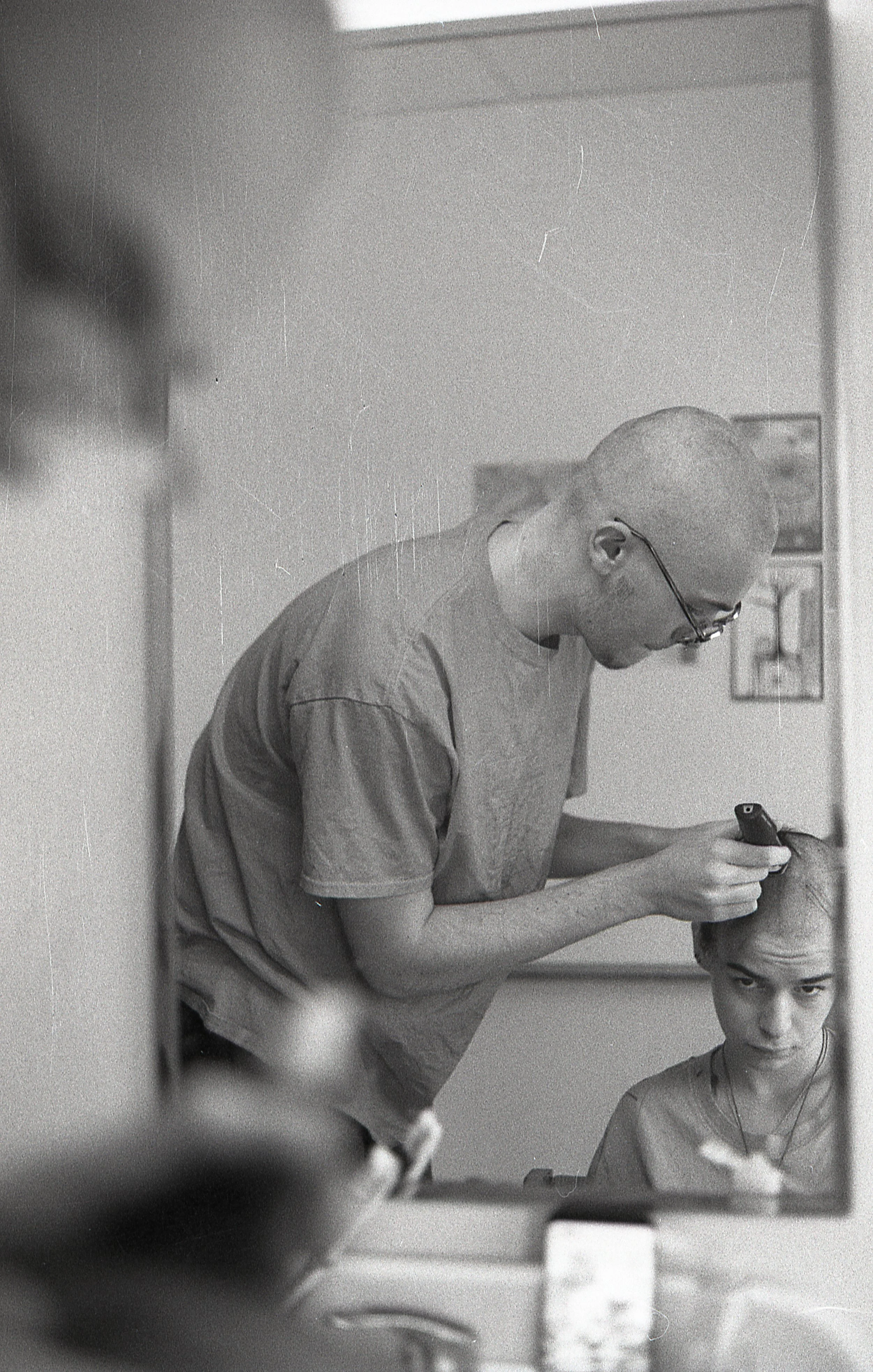 A man with glasses styling a woman's hair in a salon.