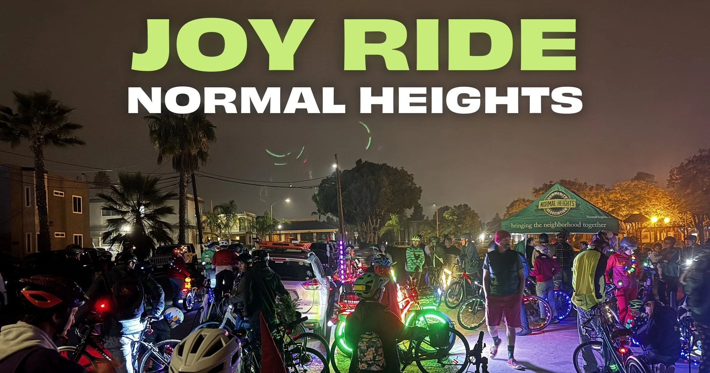 Joy Ride Normal Heights: riders with lit-up bikes gather at night at Ward Canyon Park beside the Normal Heights Community Association tent