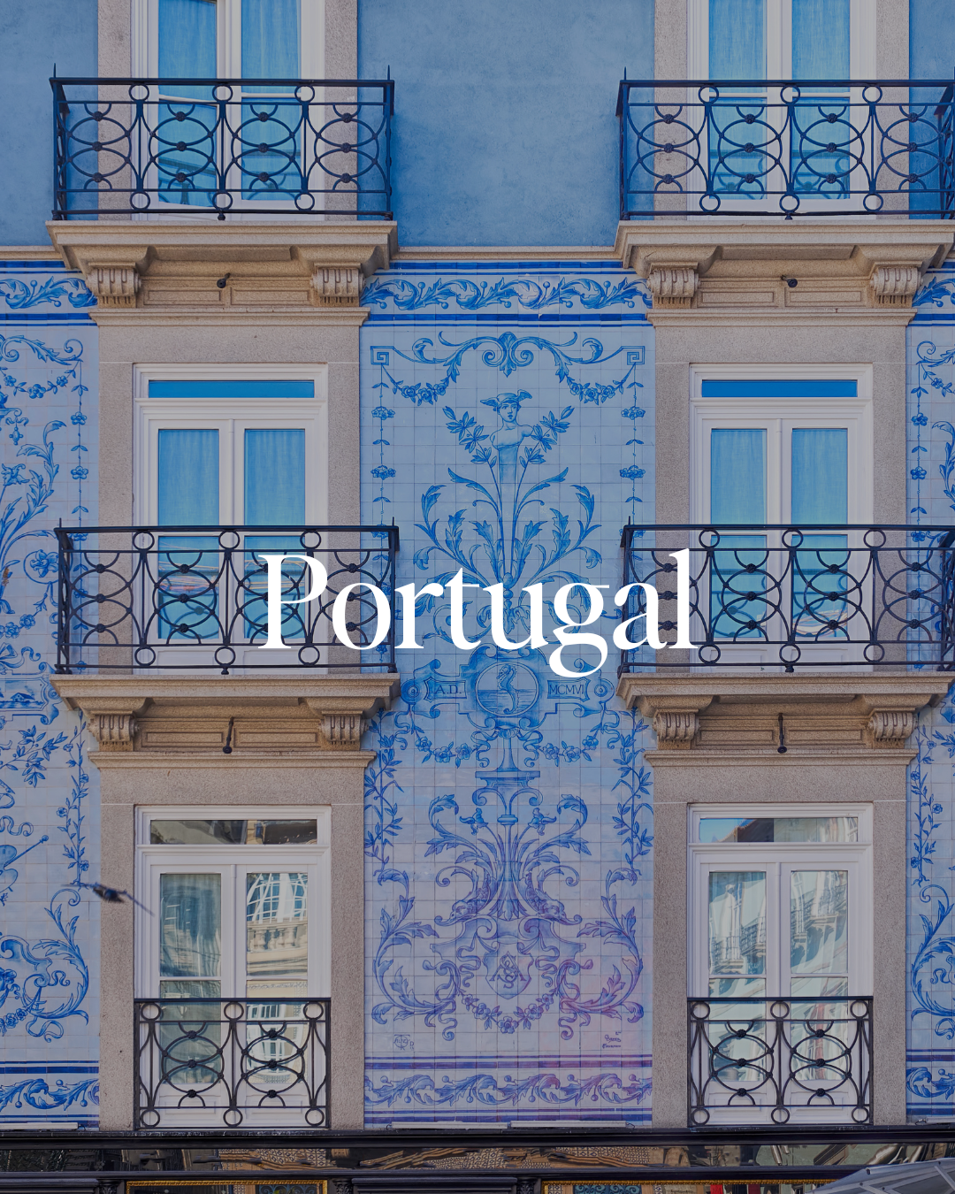 Building with traditional Portuguese tile artwork and four balconies with black wrought iron railings.
