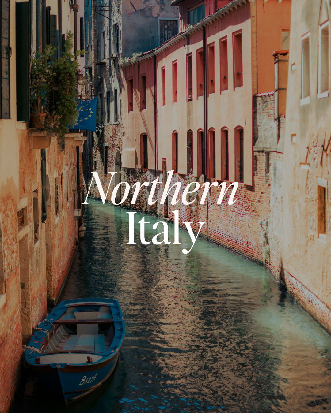 A canal in Northern Italy with buildings on both sides and a small blue boat floating in the water.