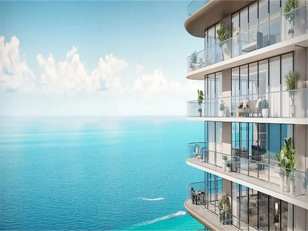 Modern multi-story apartment building with glass balconies overlooking the ocean.