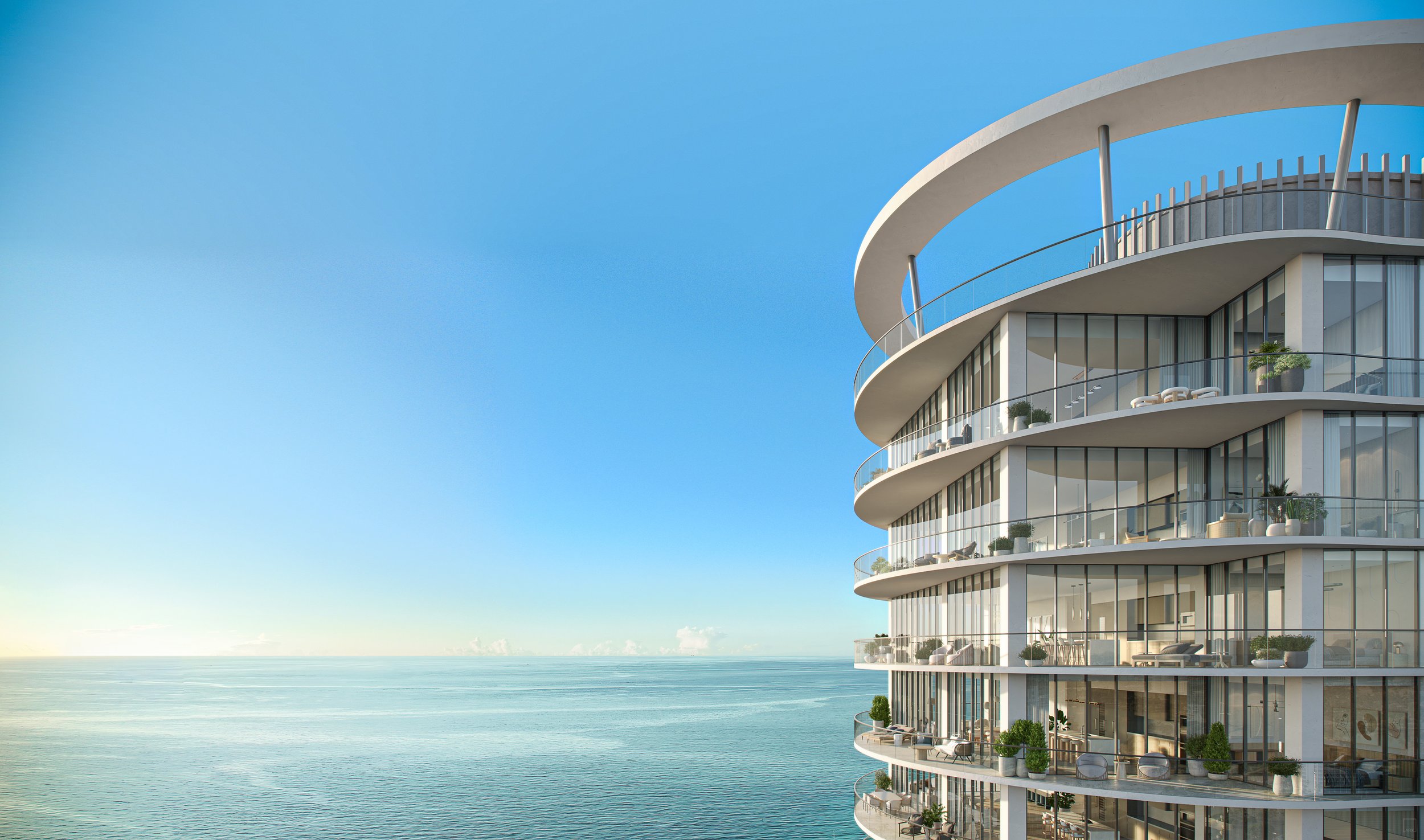 Modern multi-story building with glass balconies overlooking the ocean under a clear blue sky.