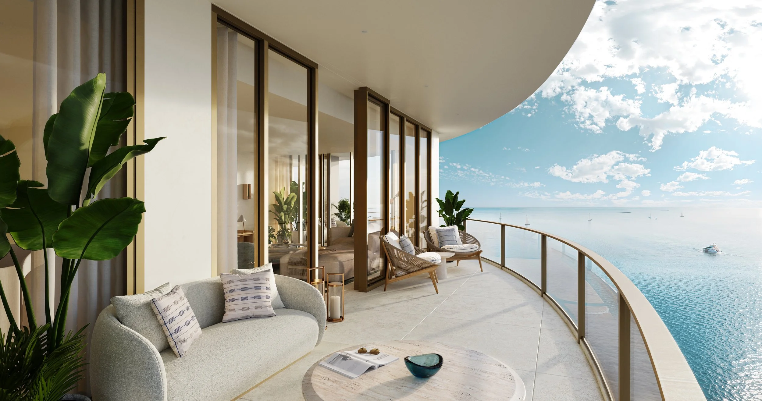 Luxury balcony with seating area overlooking ocean, with glass railing, sailboats, and a partly cloudy sky.