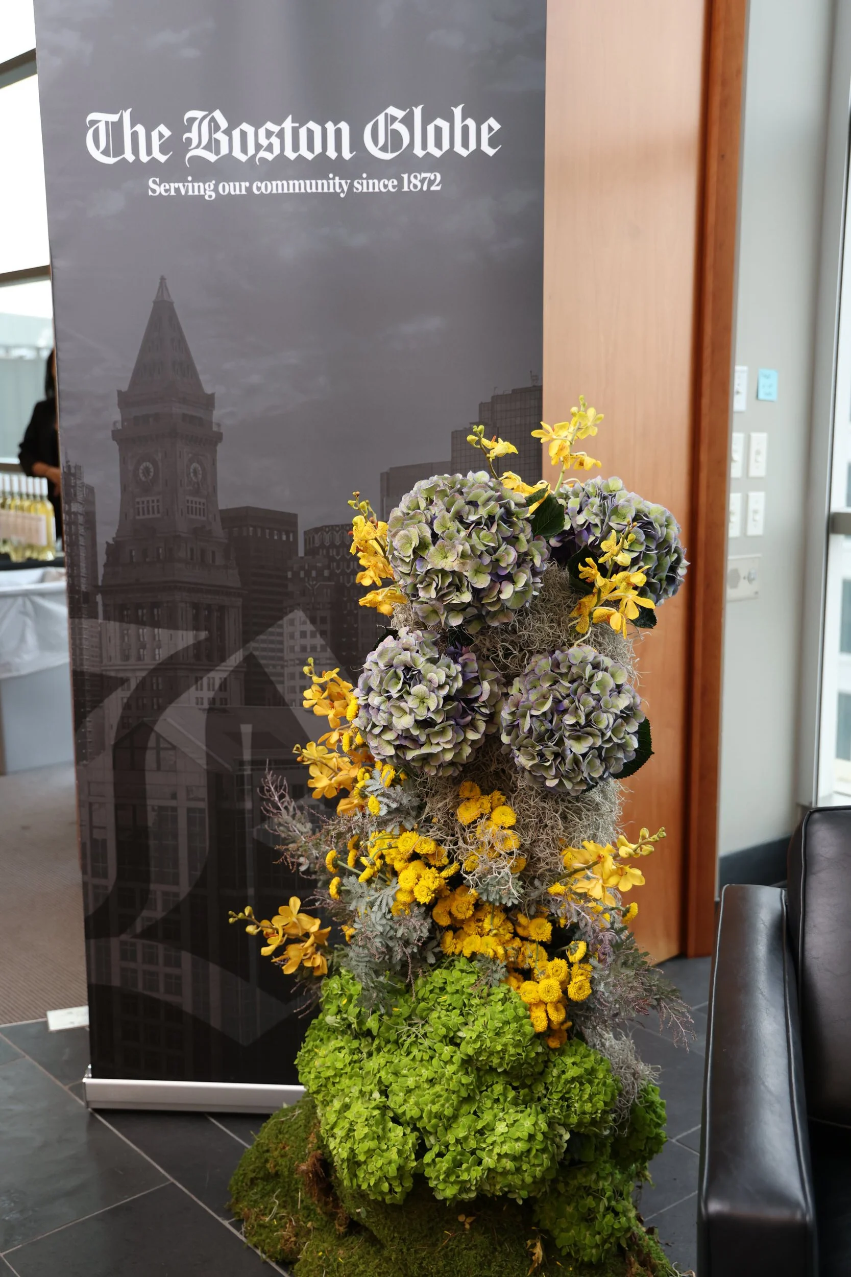  A tall grey, yellow, and green floral arrangement sitting on the ground  