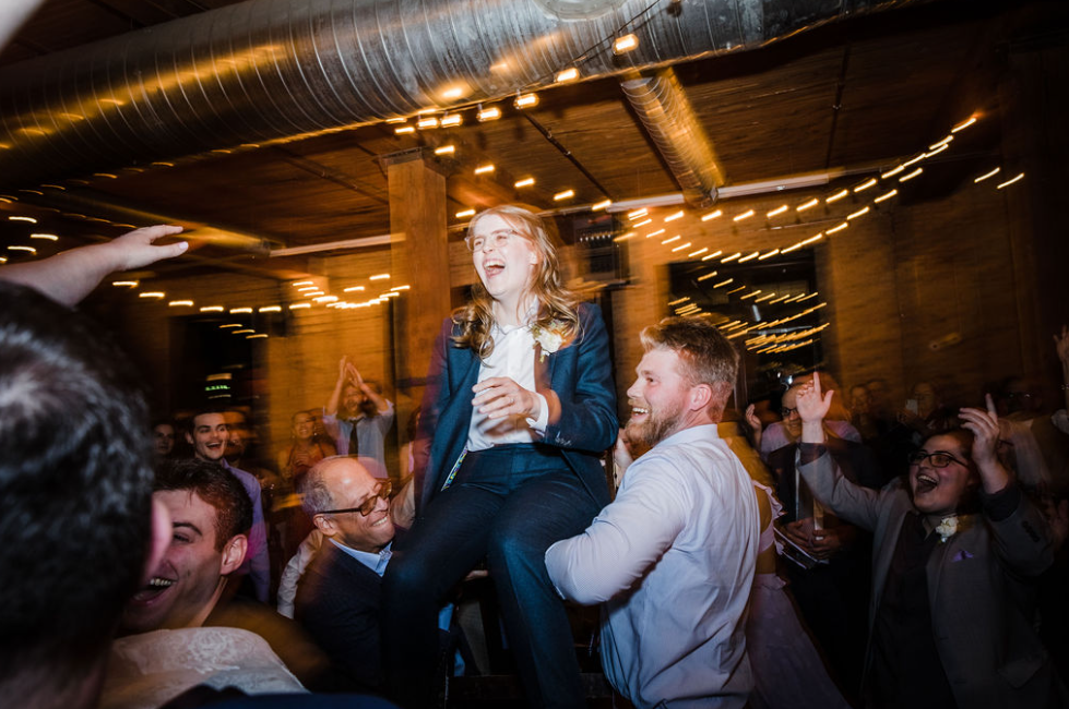 A bouquet of dark red, purple, and burgundy flowers with various foliage and small berries, placed on a white surface.
