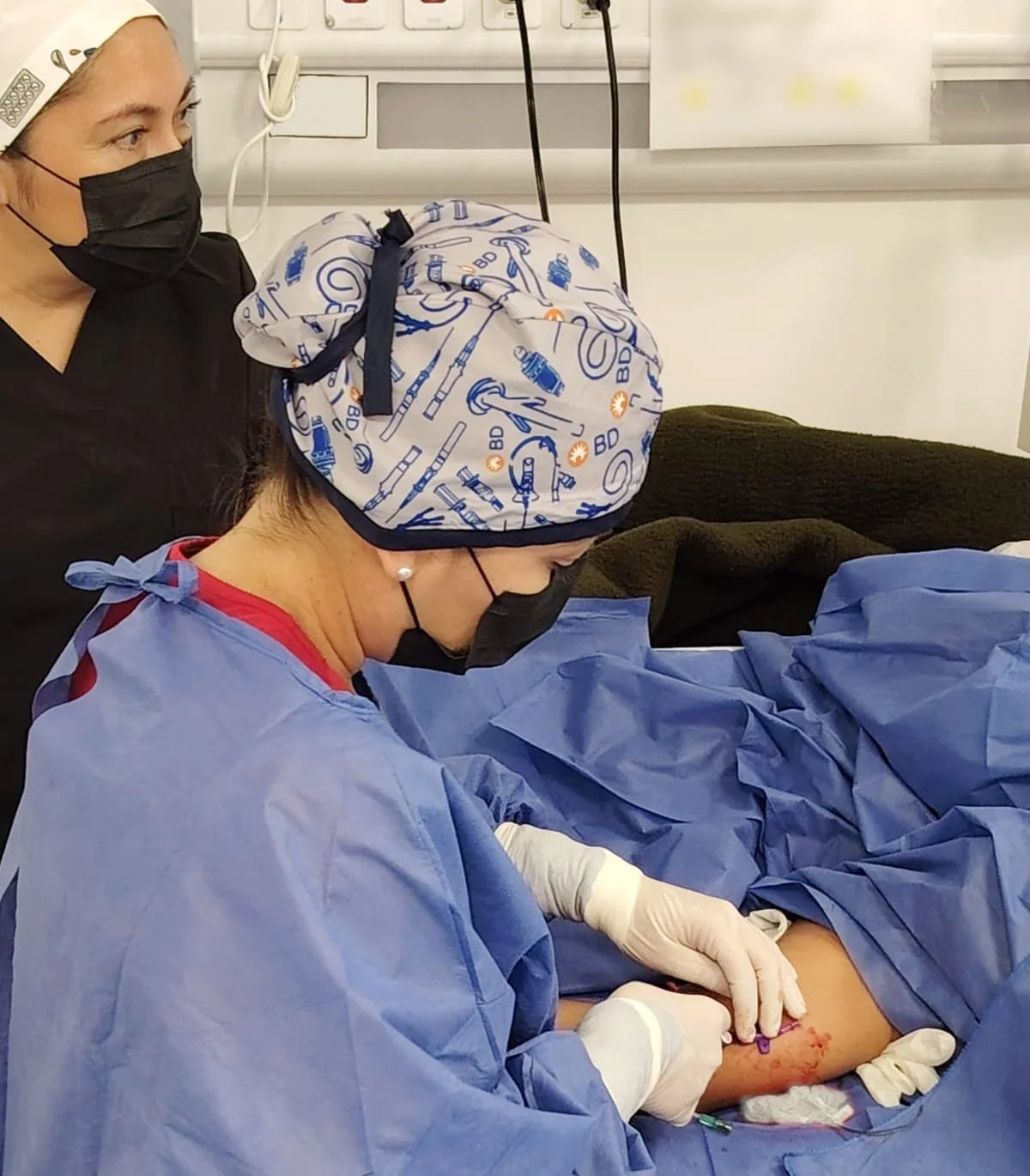 Doctora en sala de cirugía atendiendo un paciente con vendas en la pierna. ACÉRCATE Catéter PICC. ACÉRCATE Asociación para certificación y capacitación Técnica Catéter PICC