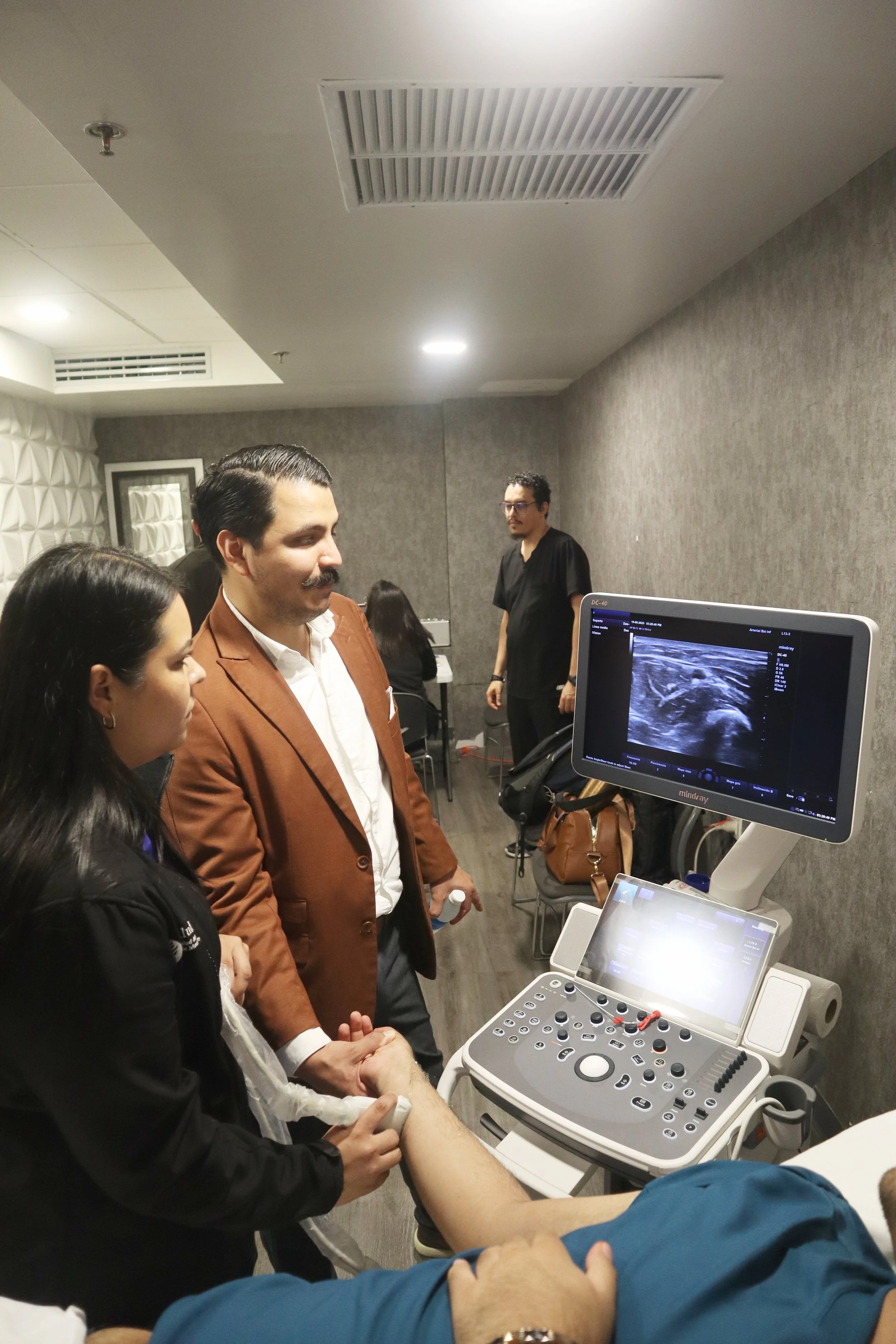 Personas en una consulta médica observando una ecografía en una pantalla. ACÉRCATE Asociación para certificación y capacitación Técnica Catéter PICC