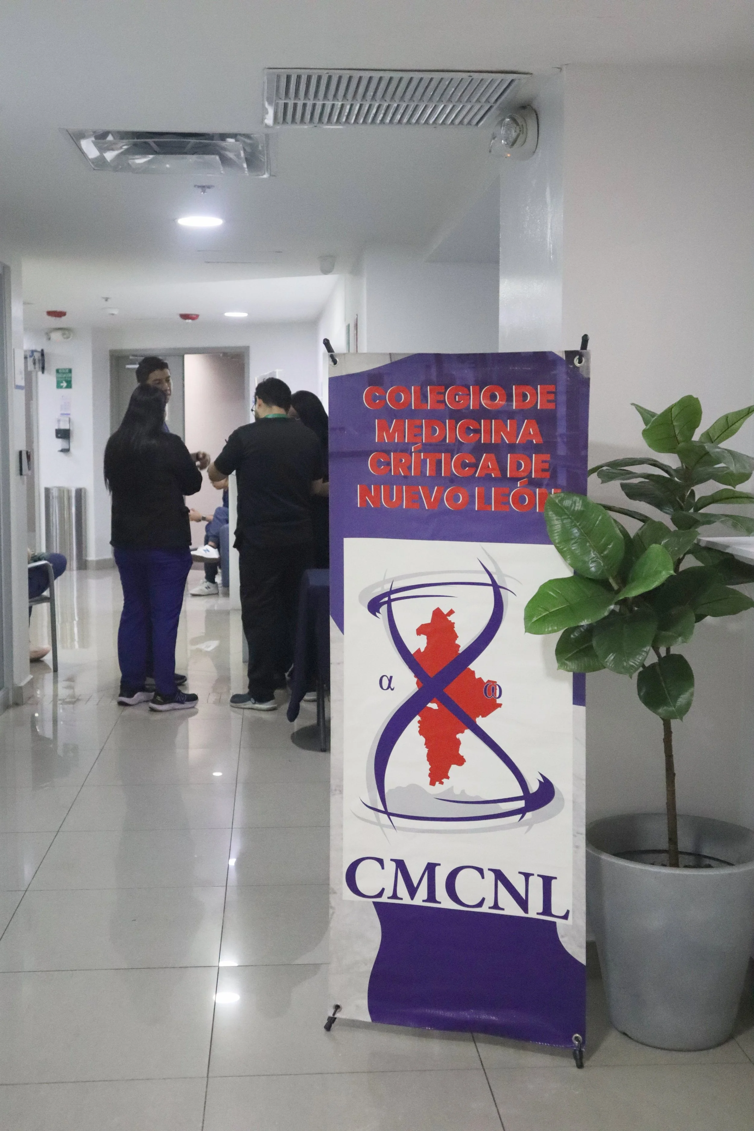Señal que indica la ubicación del Colegio de Medicina Crítica de Nuevo León, con una planta a un lado. ACÉRCATE Asociación para certificación y capacitación Técnica Catéter PICC