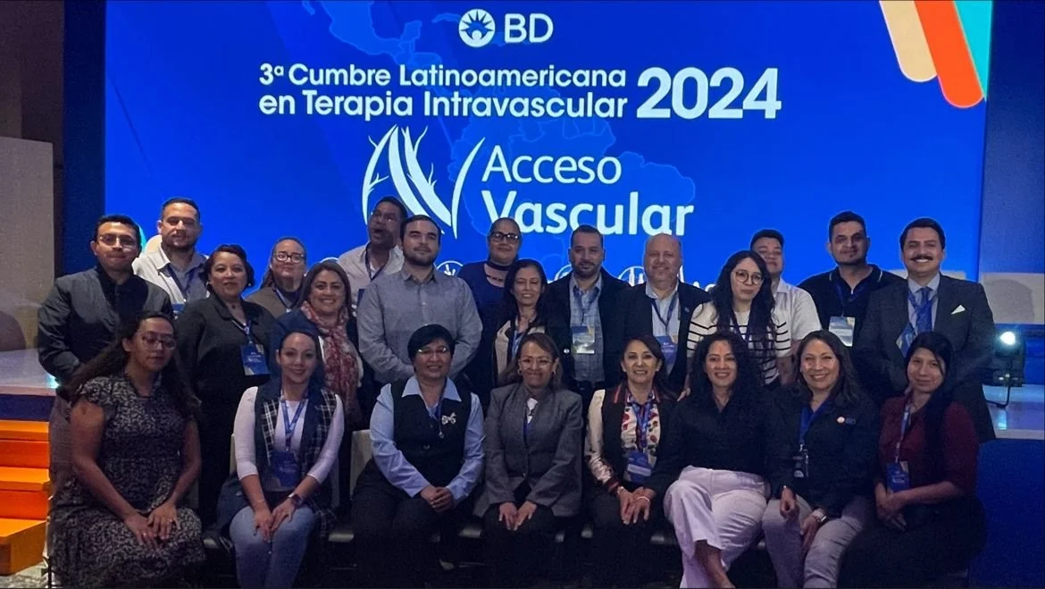 Grupo de personas en una conferencia titulada '3ª Cumbre Latinoamericana en Terapia Intravascular 2024' con un cartel que dice 'Acceso Vascular' en el fondo. ACÉRCATE Catéter PICC