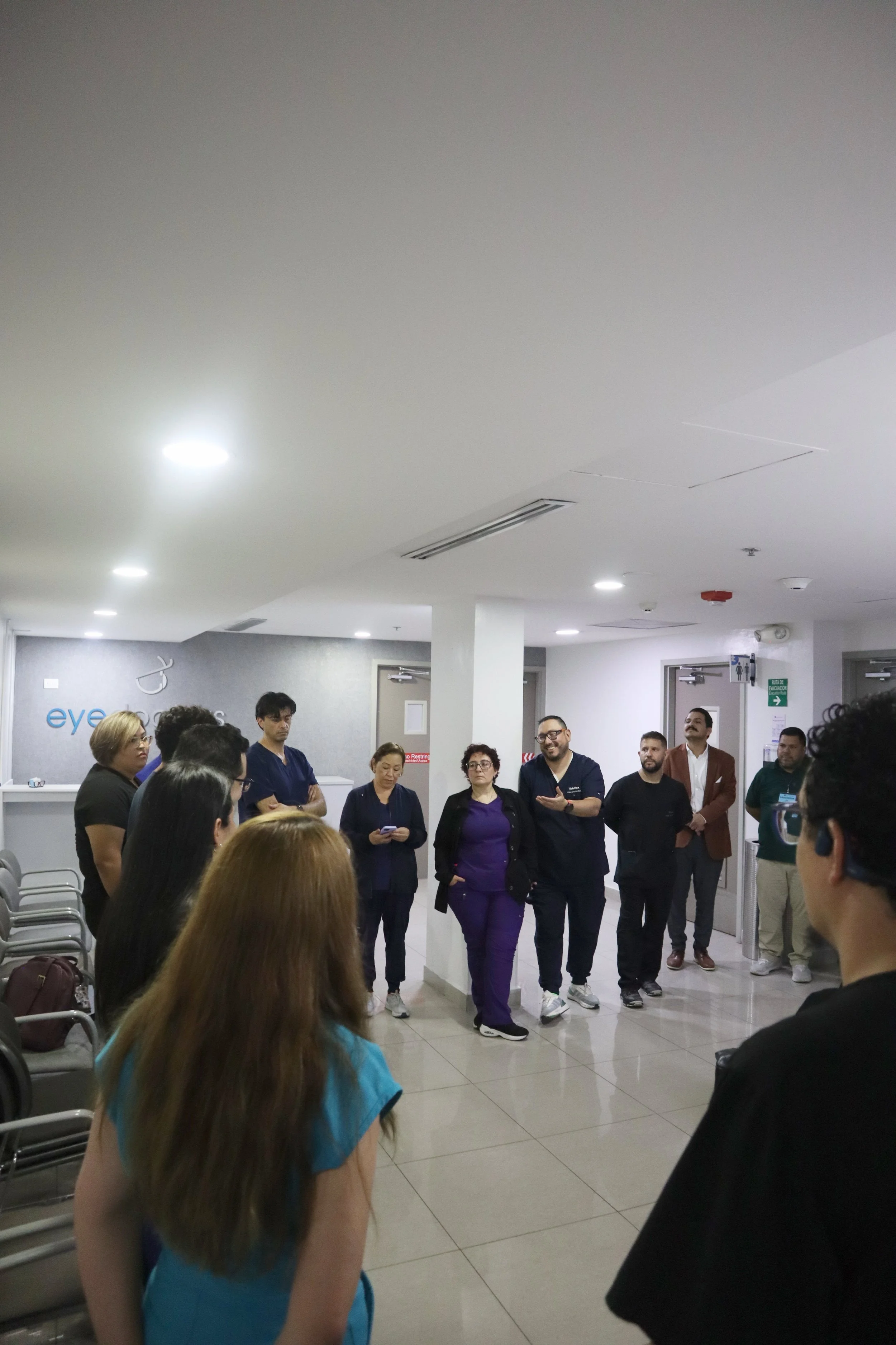 Grupo de personas de diferentes géneros y edades en una sala, participando en una reunión o charla, algunos tomando notas y otros escuchando atentamente. ACÉRCATE Asociación para certificación y capacitación Técnica Catéter PICC