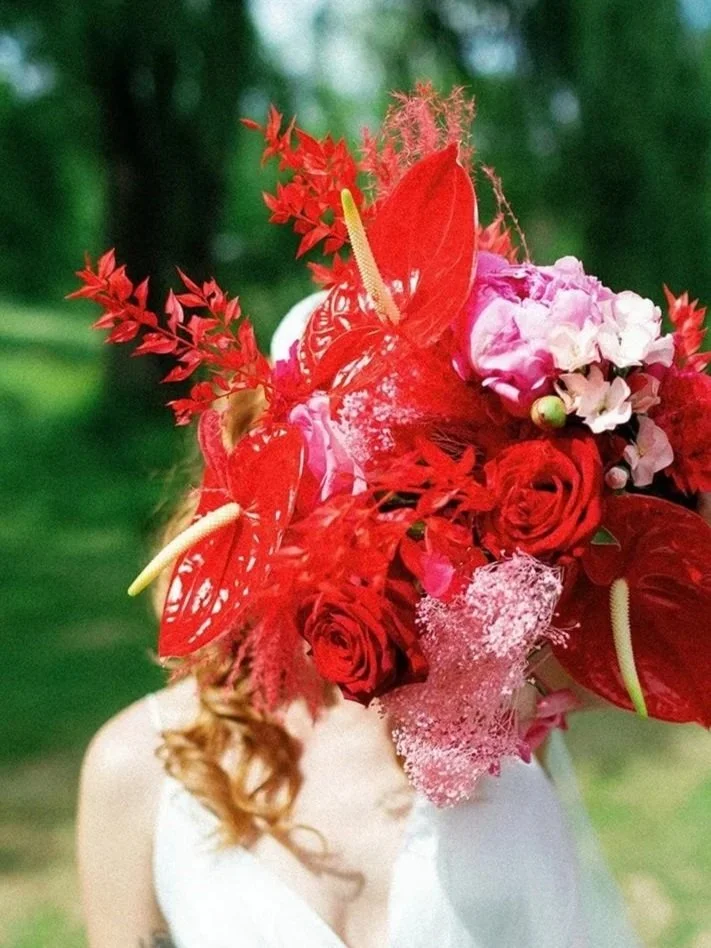 Bride with colorful bouquet covering her face