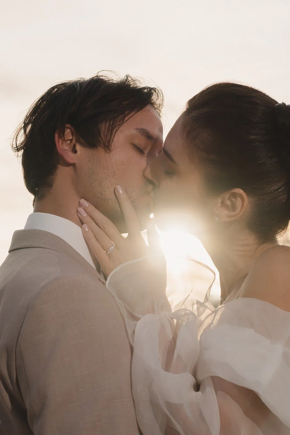 Un couple échange un baiser passionné sous la lumière dorée du coucher de soleil. Un moment brute d'amour et d'intimité.