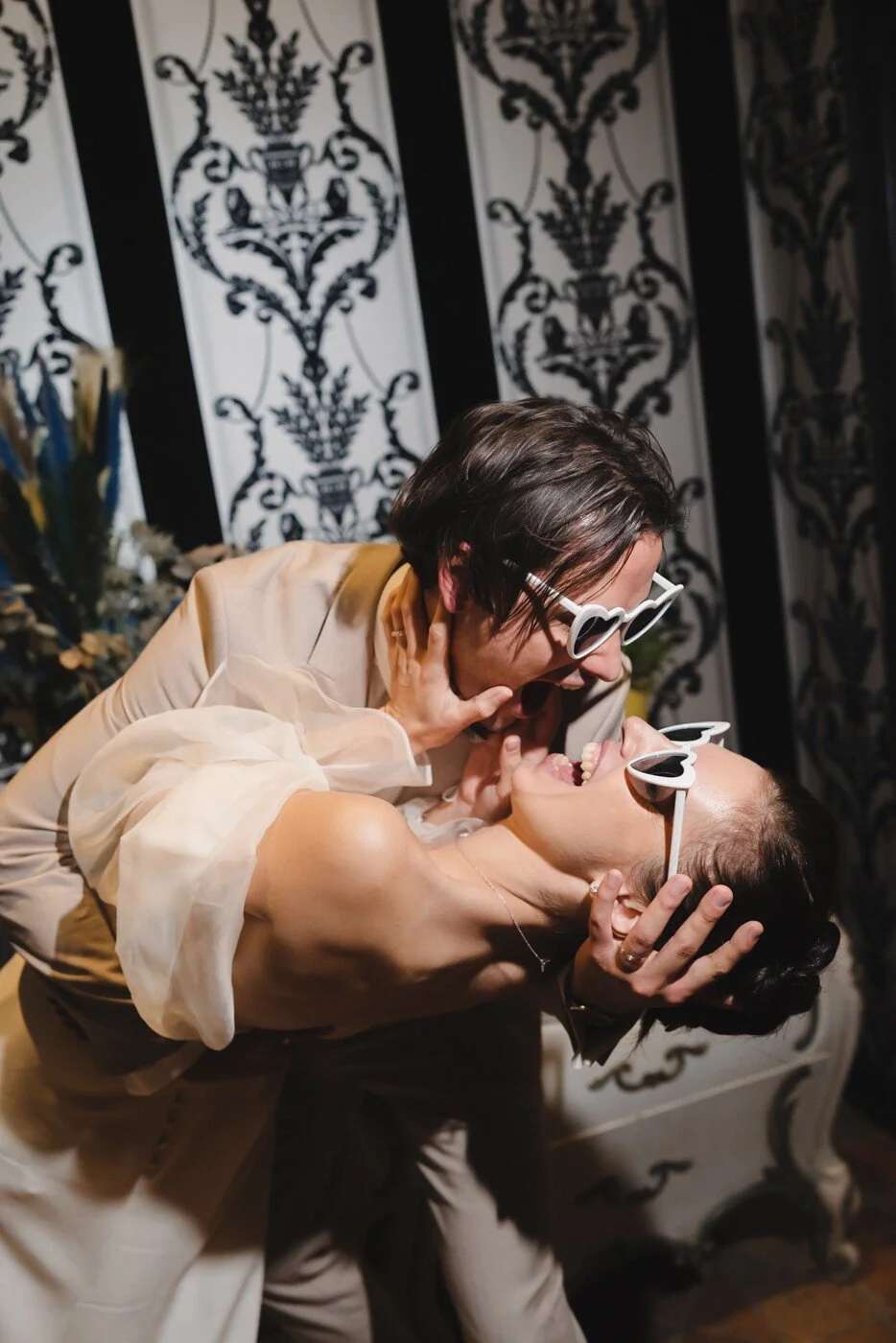 Moment de rire et de complicité entre les mariés, portant des lunettes en forme de coeur, un instant décalé et plein de joie.