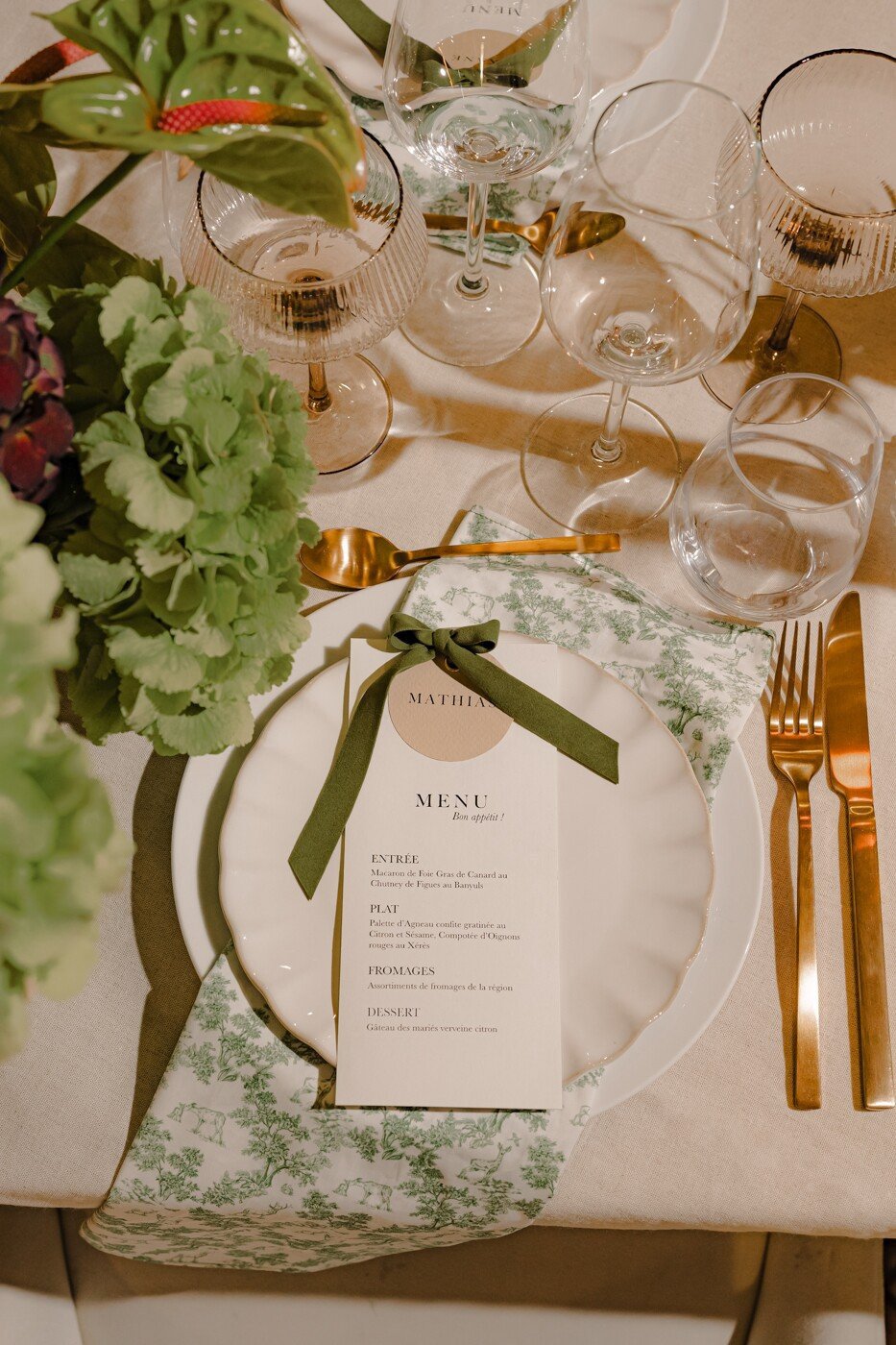Une table soigneusement dressé avec un menu élégant, des couvert dorés et des détails floraux pour un diner de mariage raffiné.