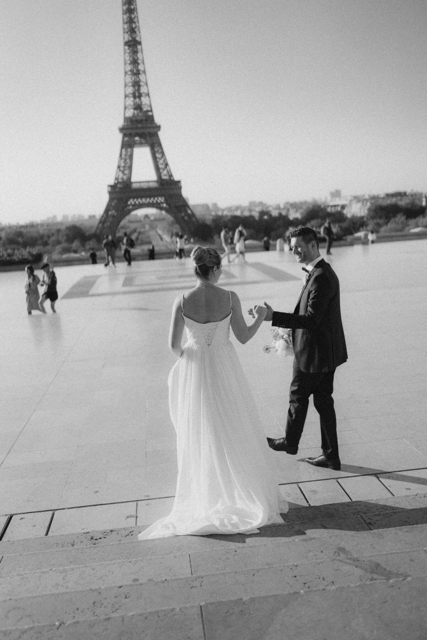 un couple en tenue de mariage, au Trocadéro à paris avec vue sur la tour Eiffel