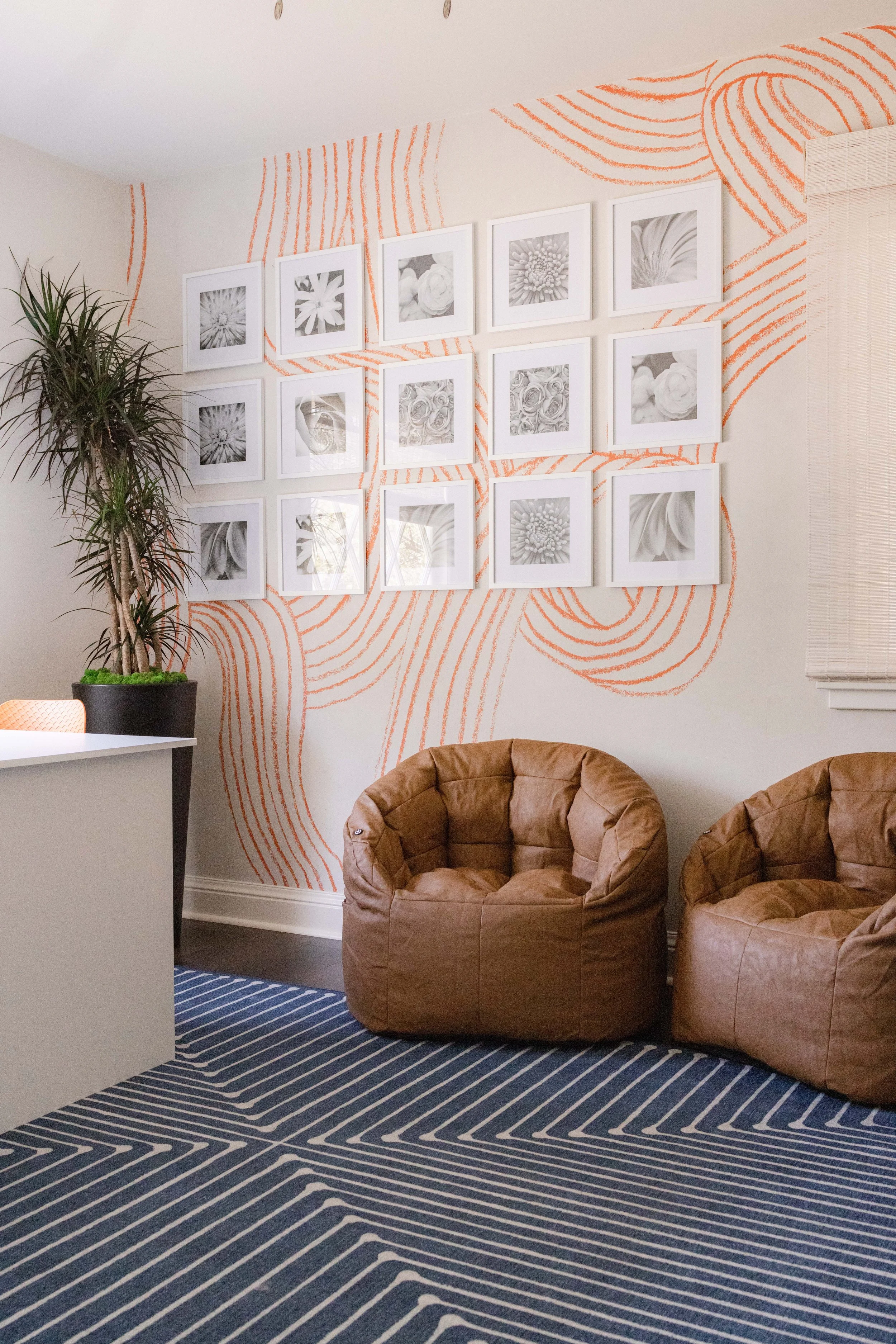 South Bay kids playroom with wall art, two brown leather pouf chairs, potted plant, and a striped blue area rug interior design by Michelle Accetta.