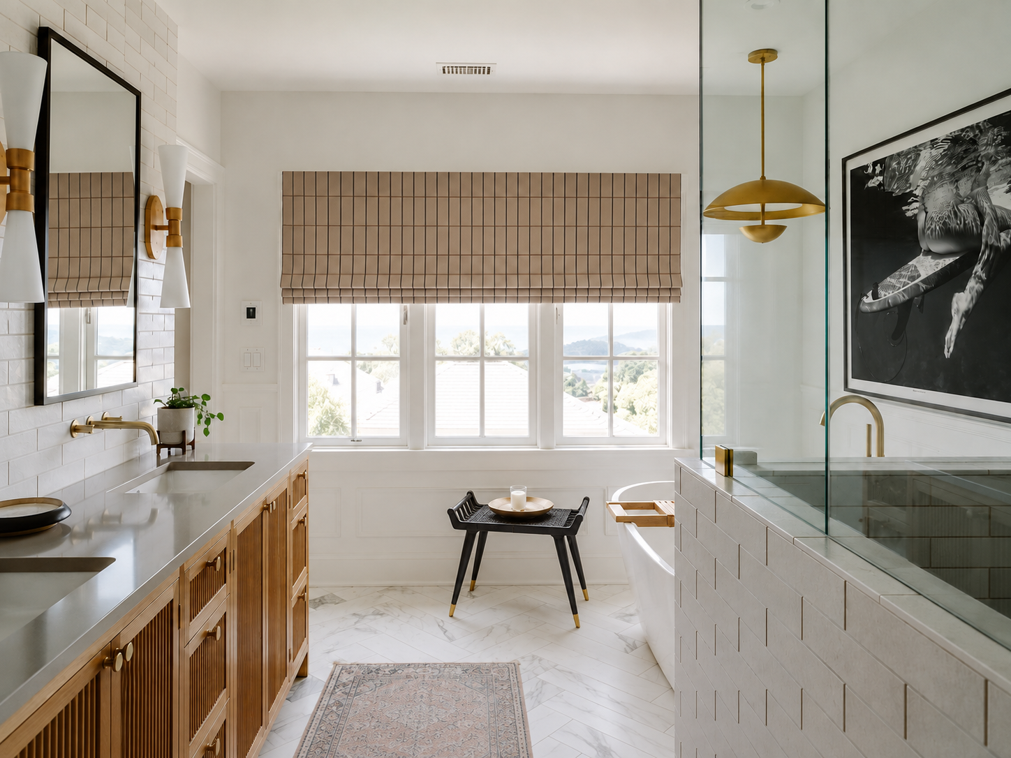Bright modern primary bathroom with warm wood cabinetry, brass fixtures, white tile, a glass-enclosed soaking tub, tailored Roman shades, and soft natural light.