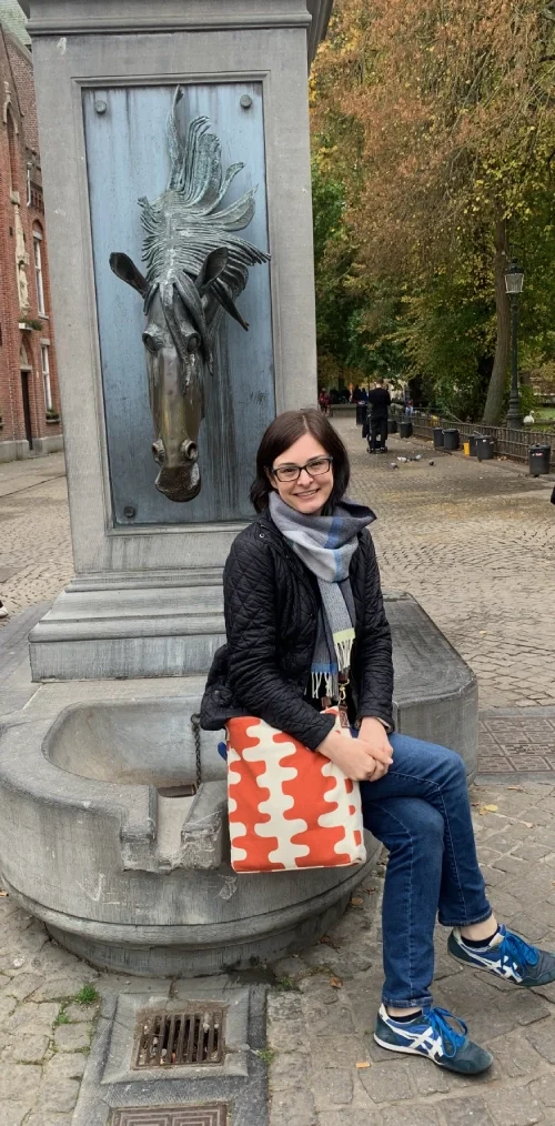 Img of Hilary sitting on the horse head fountain in Wijngaardplein in Bruges, Belgium