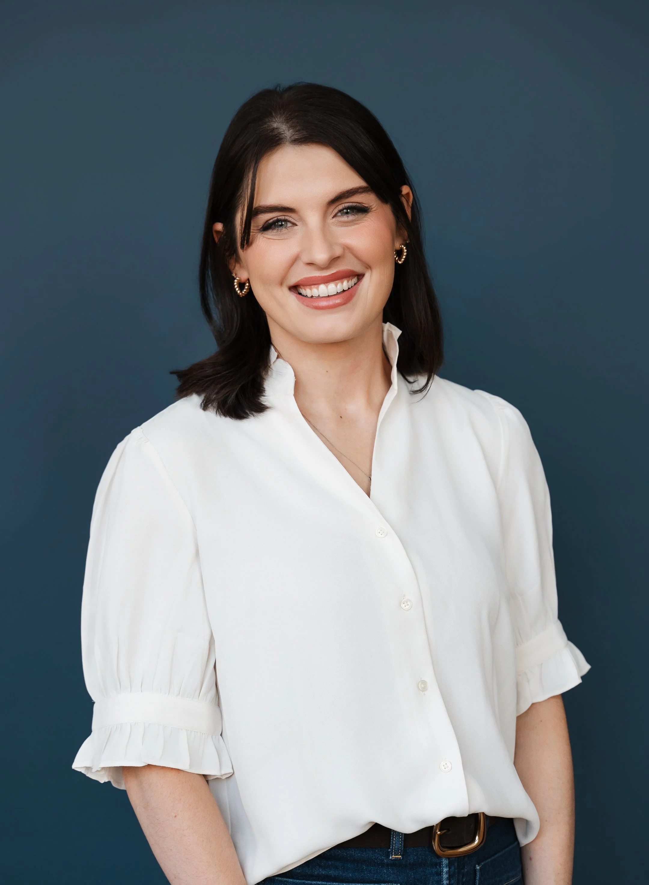 female with dark hair, glowing skin and beautiful makeup smiling for headshot